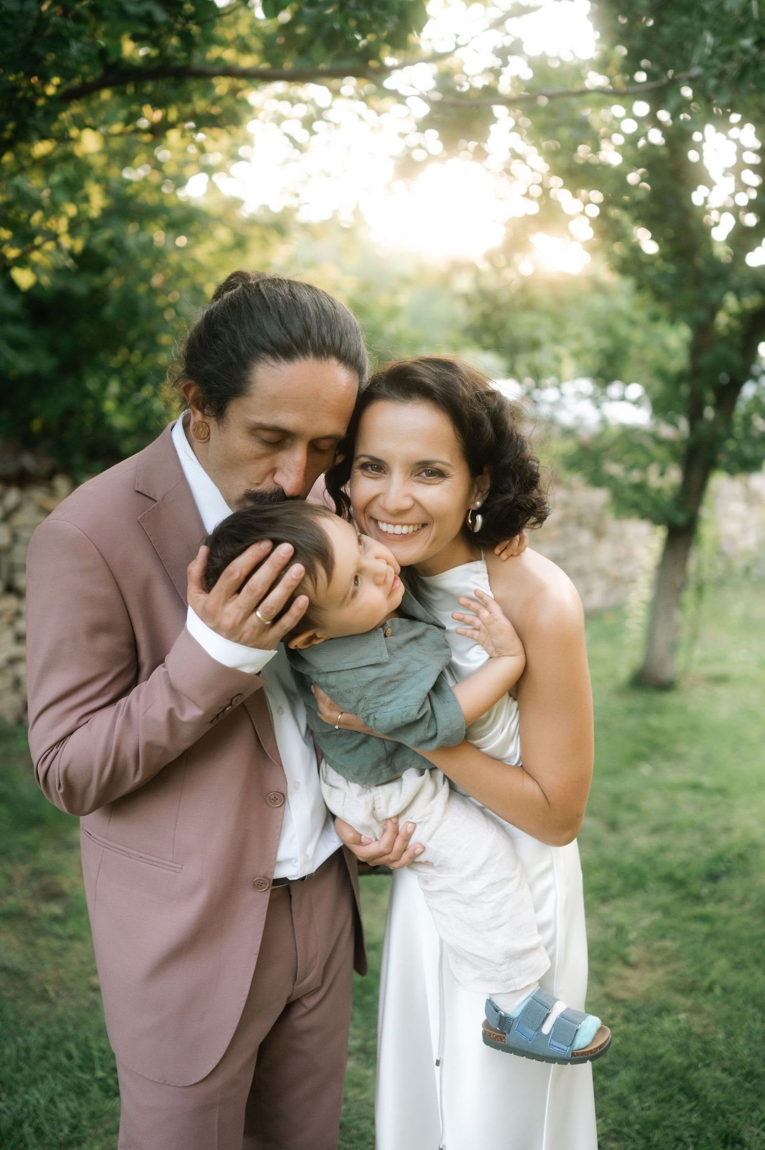 A couple shares a tender moment outdoors during their wedding photoshoot in a natural garden setting.