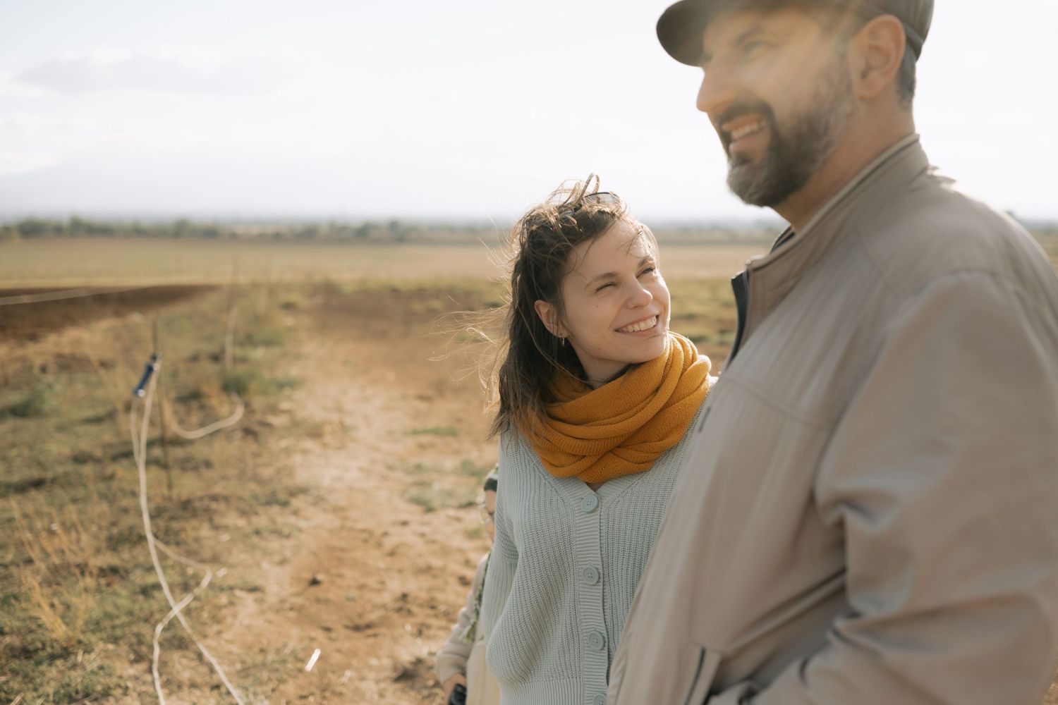 Couple embraces in a romantic moment while standing in a golden field at sunset.