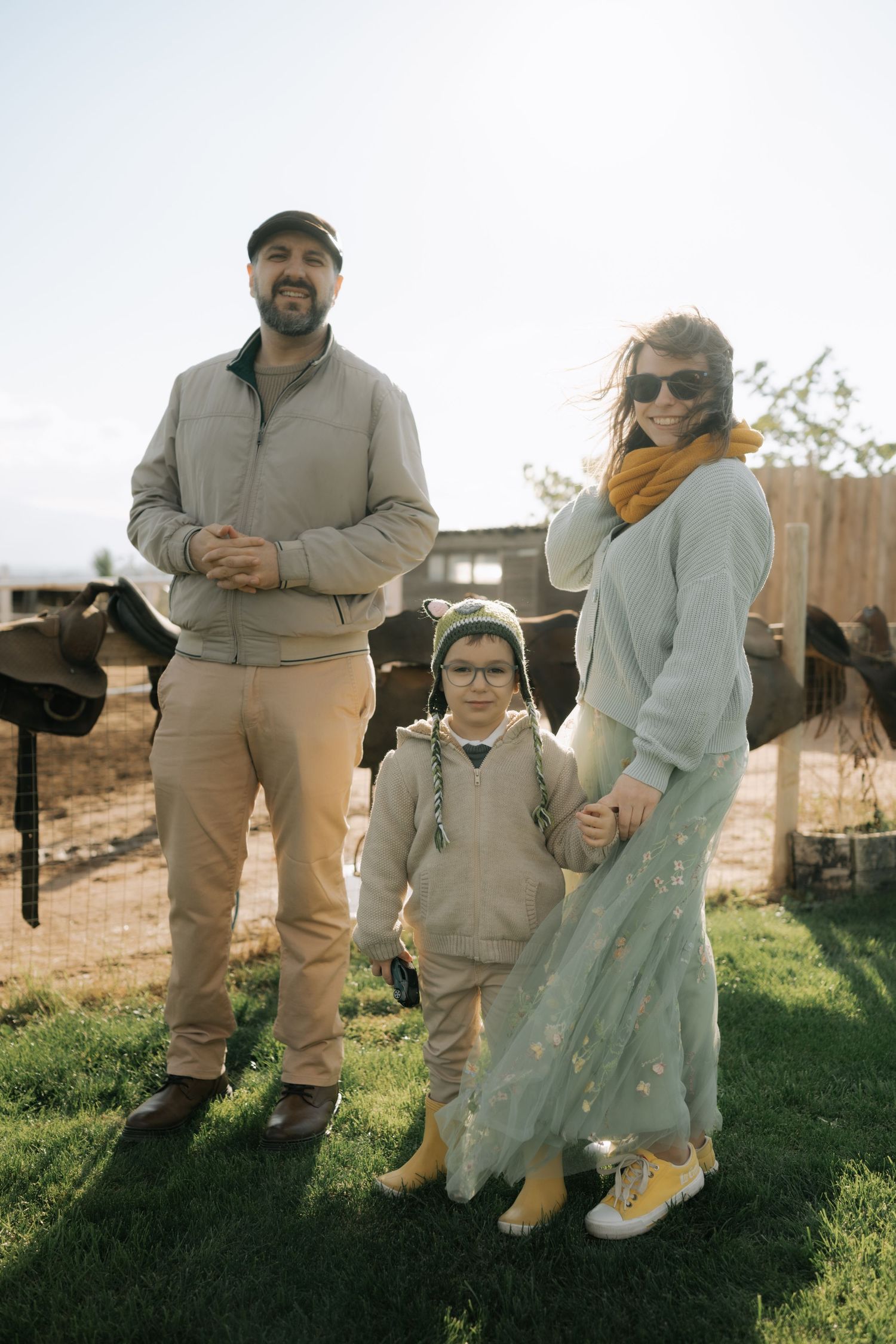 A group sits together outdoors on a grassy hill during golden hour wearing coordinated beige and cream colored outfits.