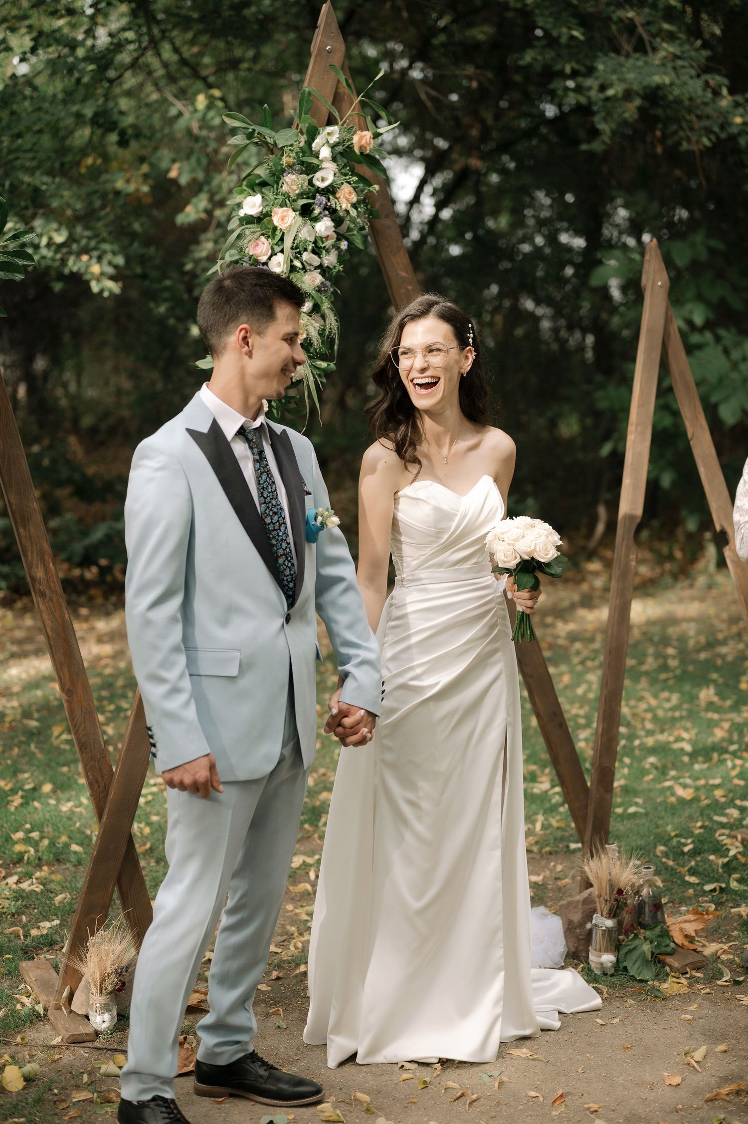 A couple shares joyful moments together in an outdoor setting with autumn leaves on the ground.
