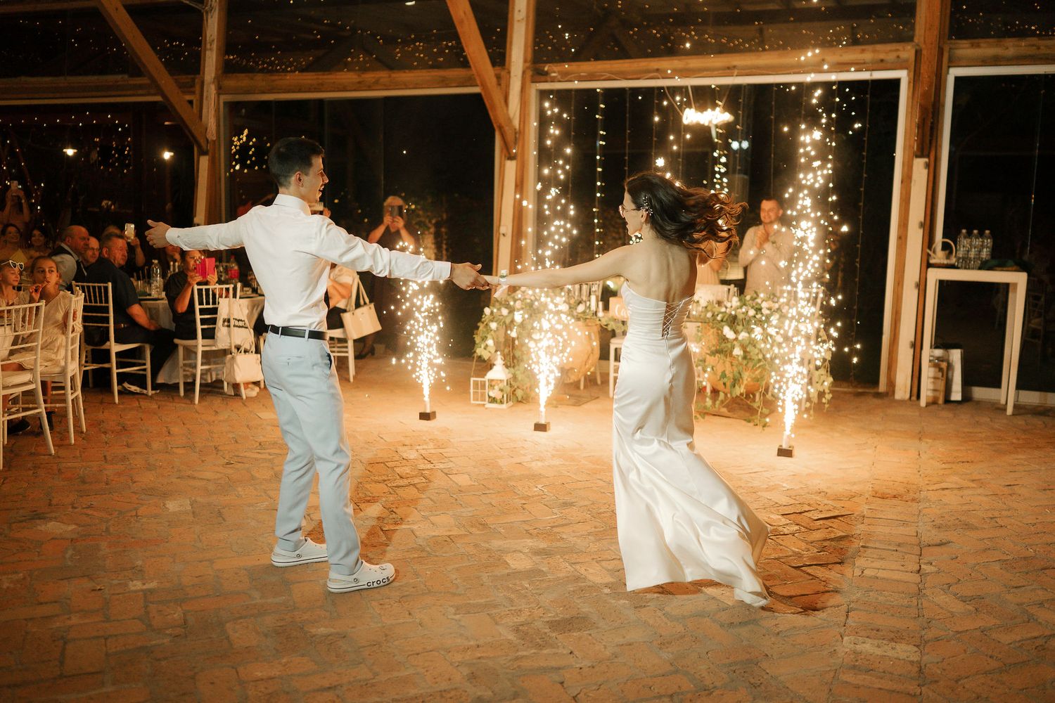 Couple performs a romantic first dance at their rustic barn wedding reception with sparklers illuminating the scene.