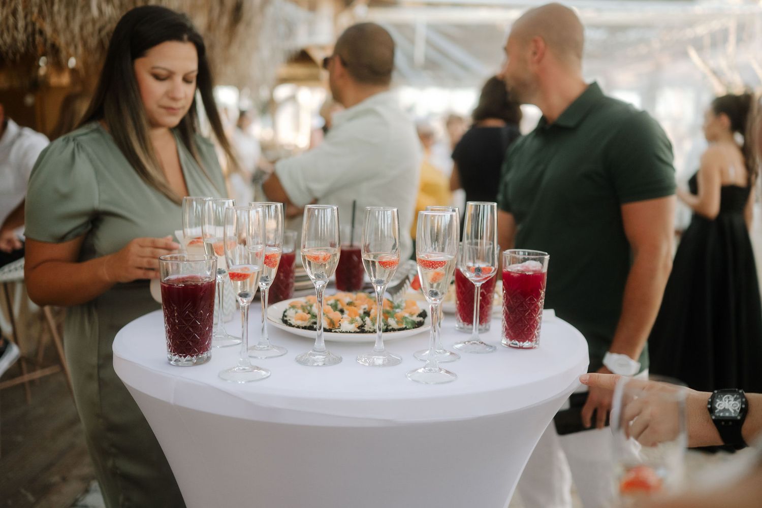 People enjoying drinks and appetizers at an elegant cocktail reception with white tablecloths and glassware.