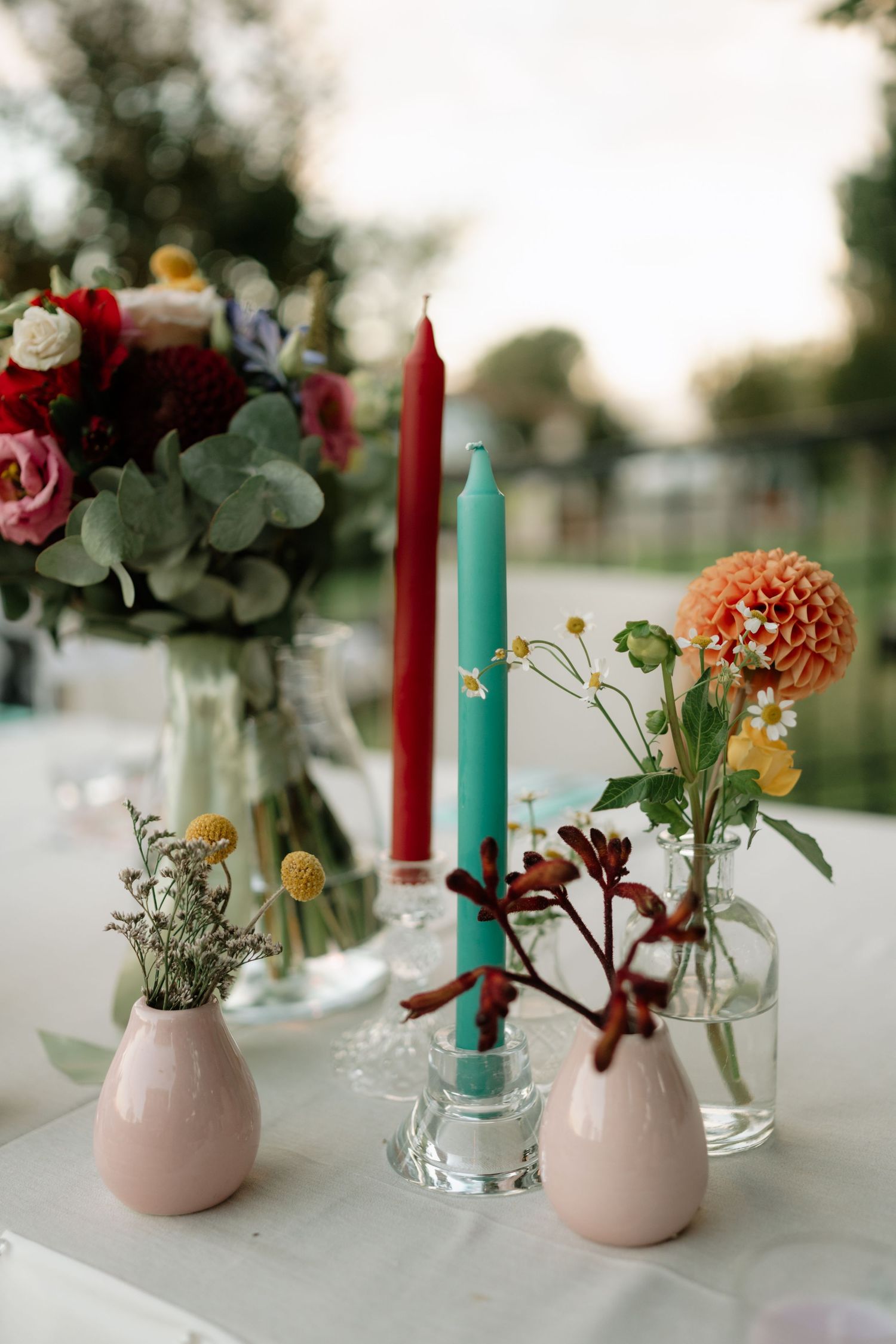 Pink ceramic vases with colorful taper candles and delicate floral arrangements create an elegant table centerpiece display.