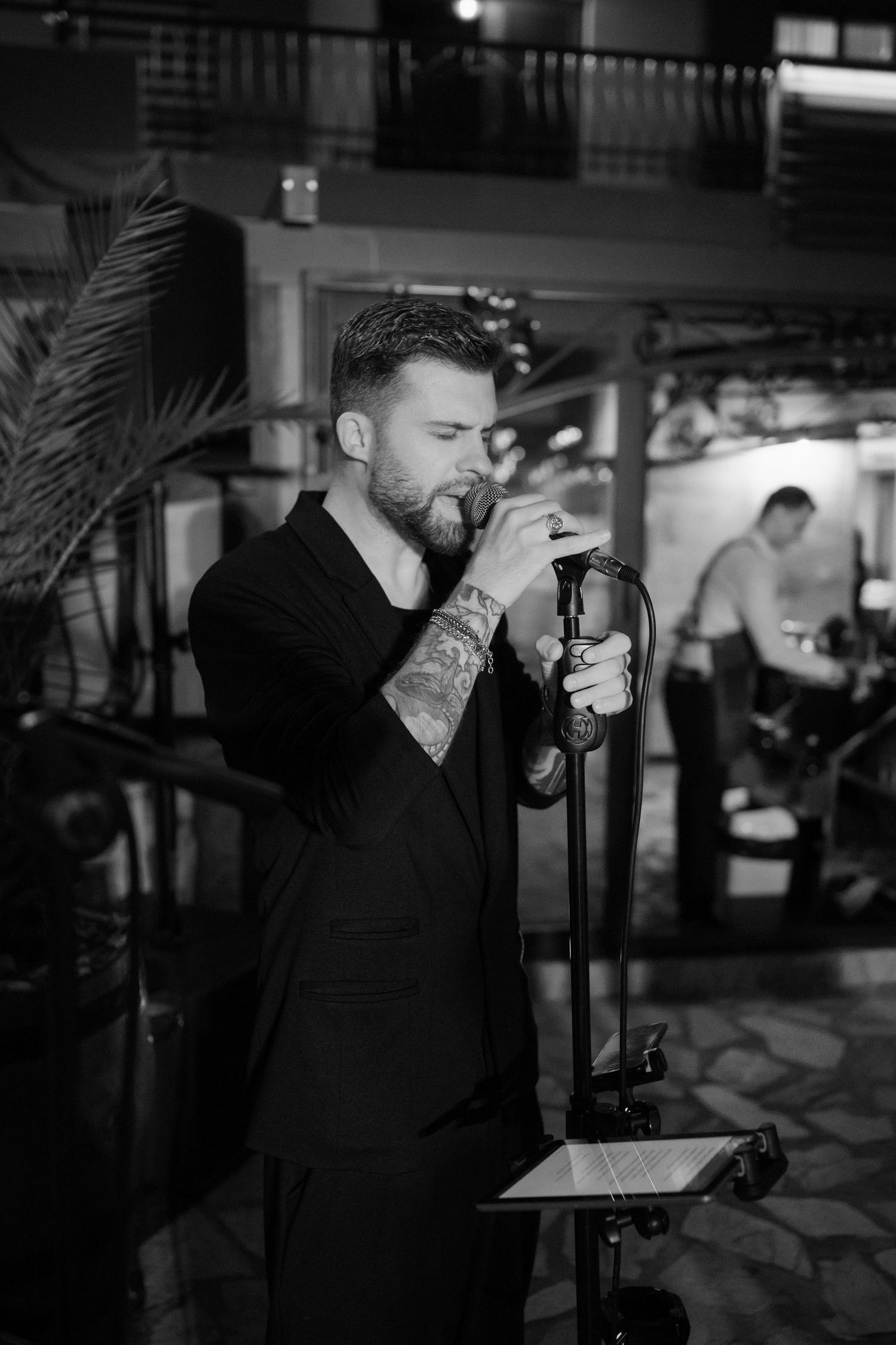A black and white photo series shows a person in dark clothing singing into a microphone on stage.