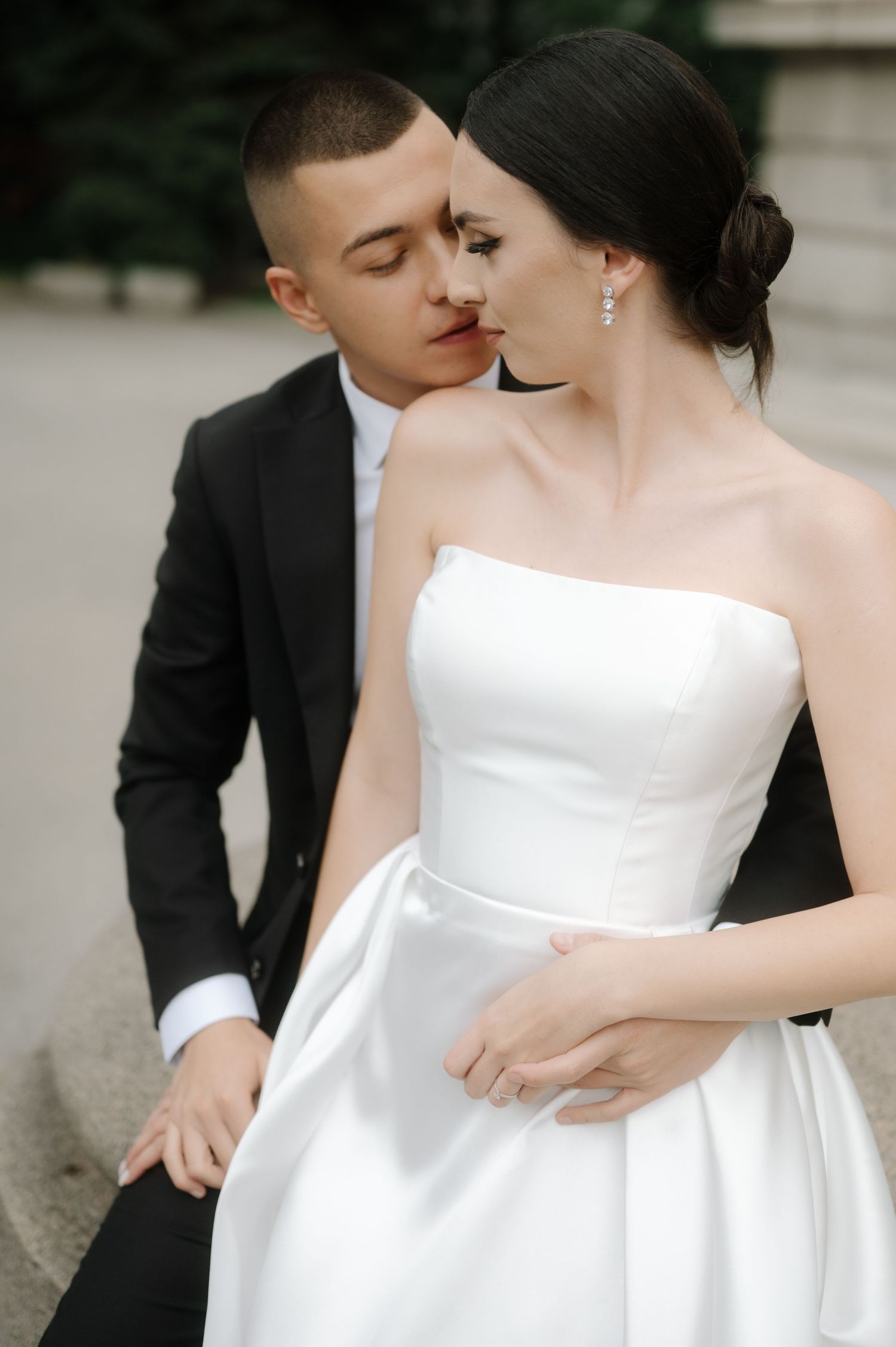 A romantic wedding couple in elegant attire share intimate moments in a series of black and white photographs.