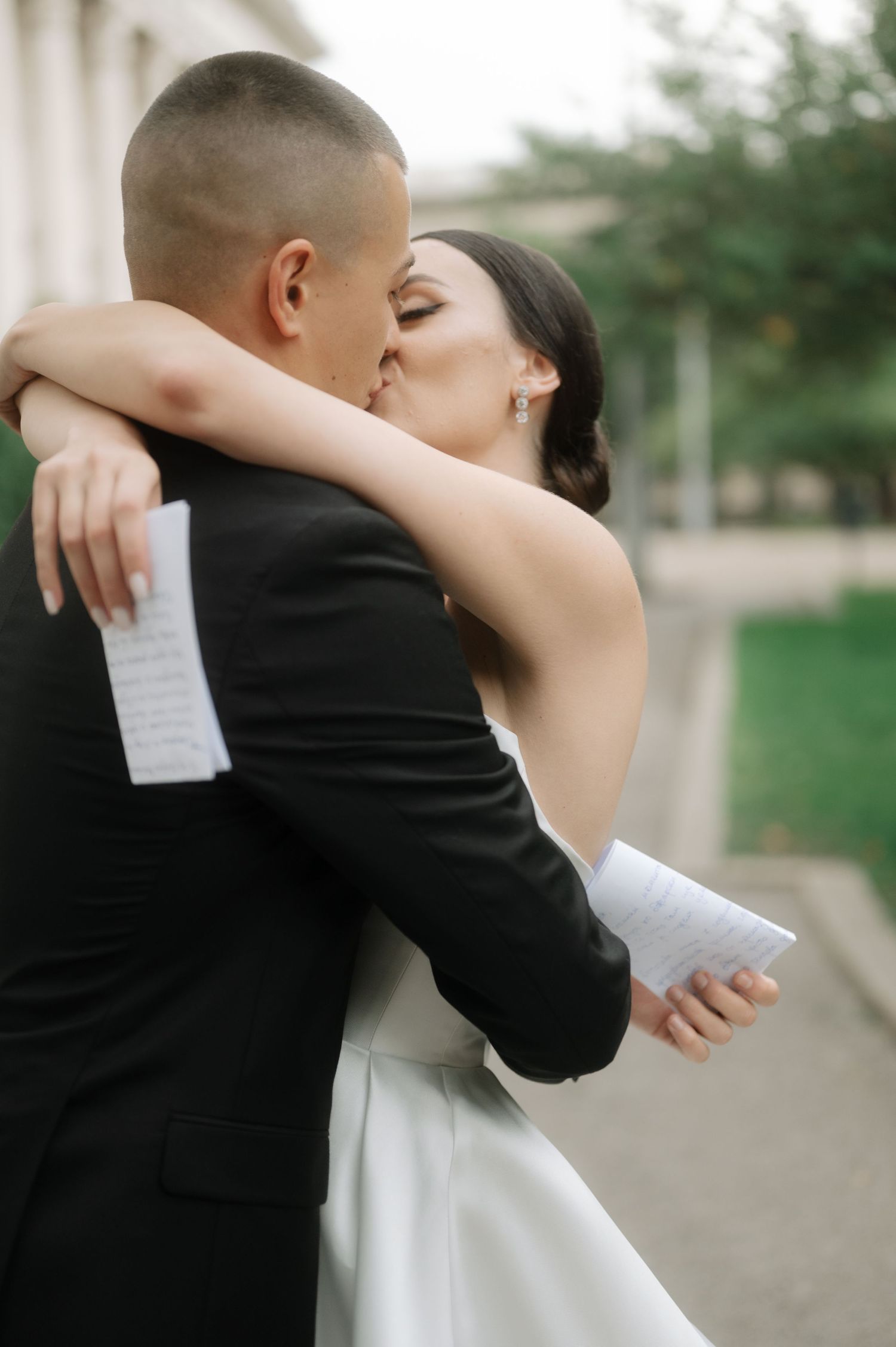 Couple sharing an intimate moment during their wedding ceremony while holding papers.