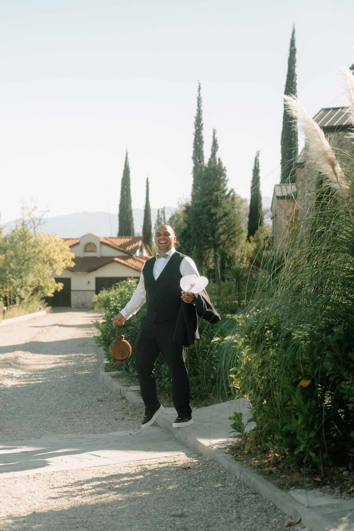 A sequence of four action shots showing a person jumping and doing tricks in a suburban driveway with cypress trees nearby.