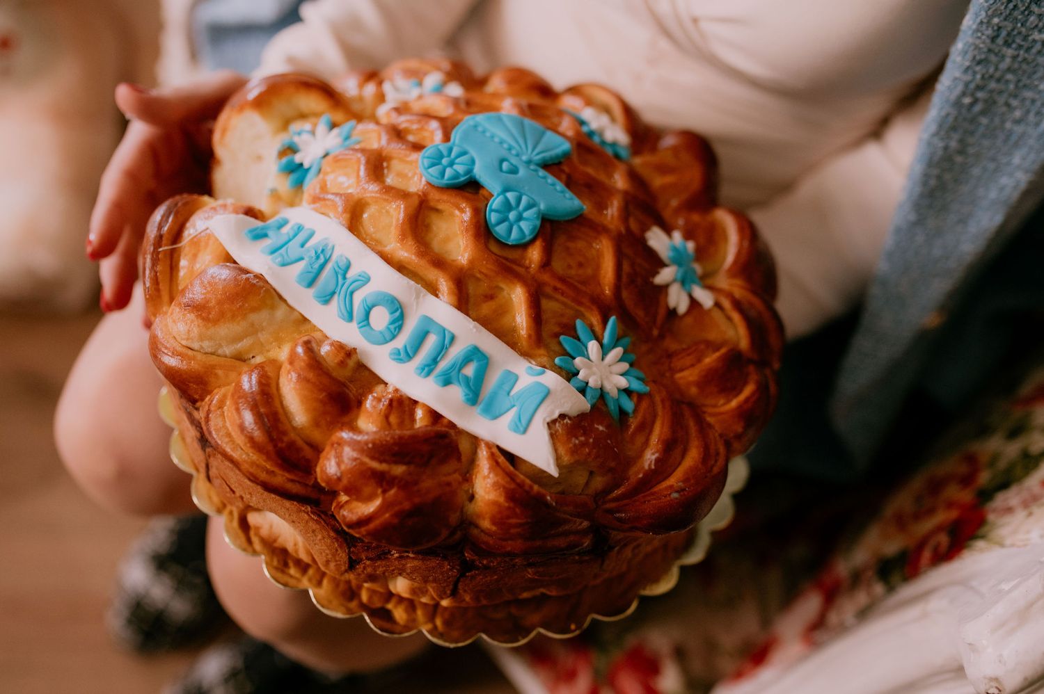 Hands holding a decorated gingerbread cookie with blue and white icing snowflakes and winter designs.