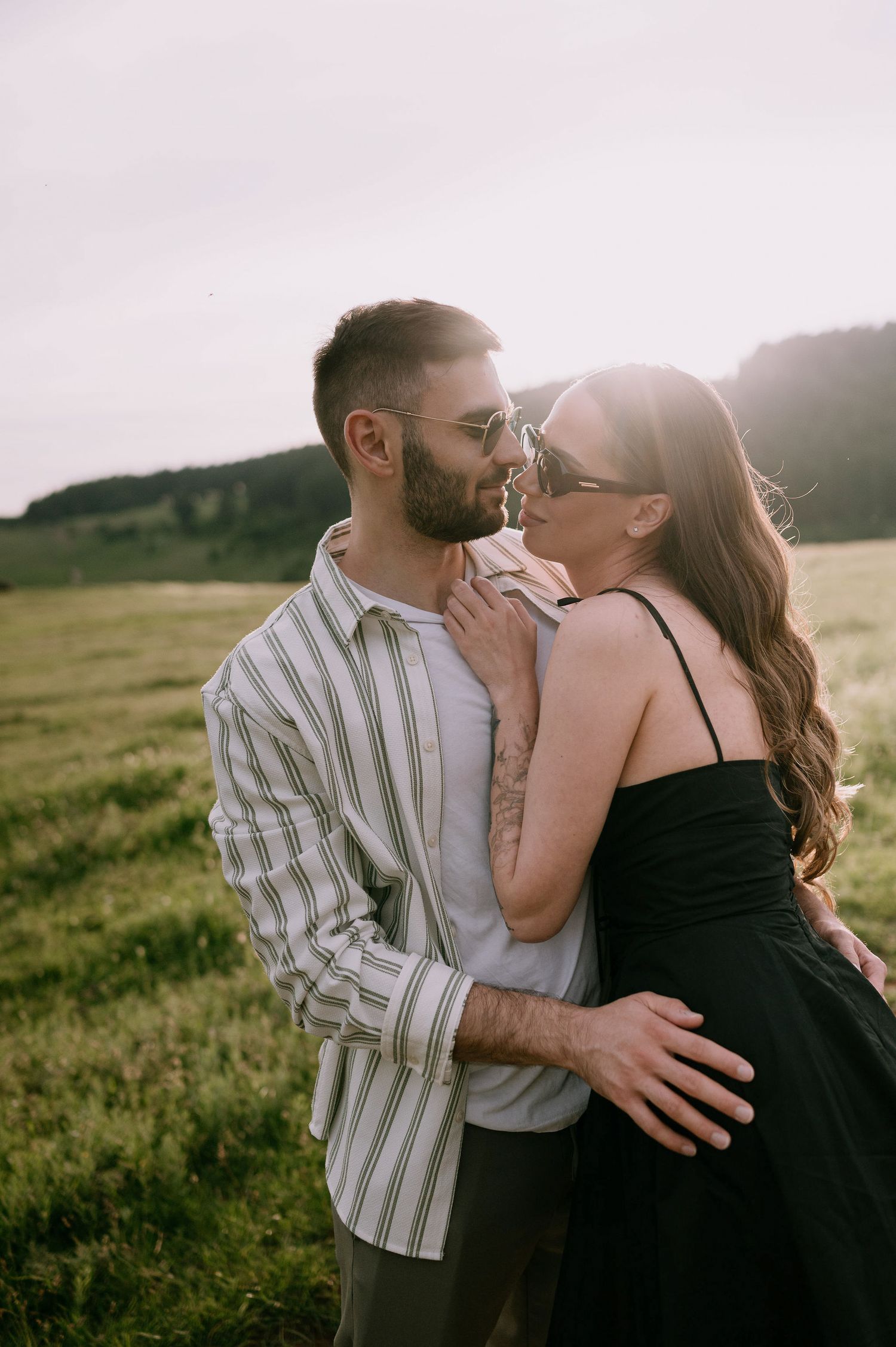 A romantic couple shares tender kisses in a series of candid photos taken in a sunlit meadow at golden hour.