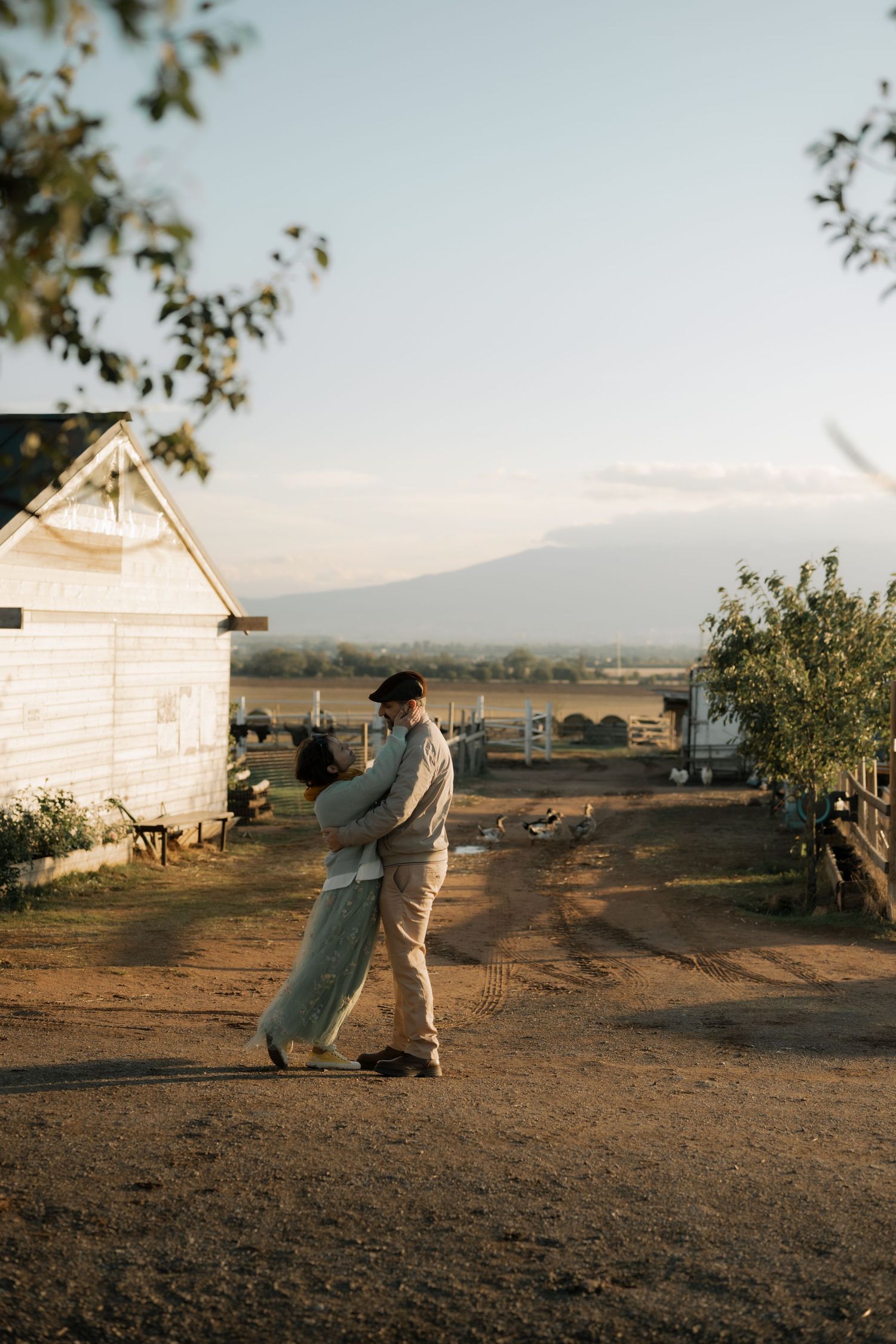 Three sequential images show figures in a dusty rural landscape at sunset with small white buildings in the background.