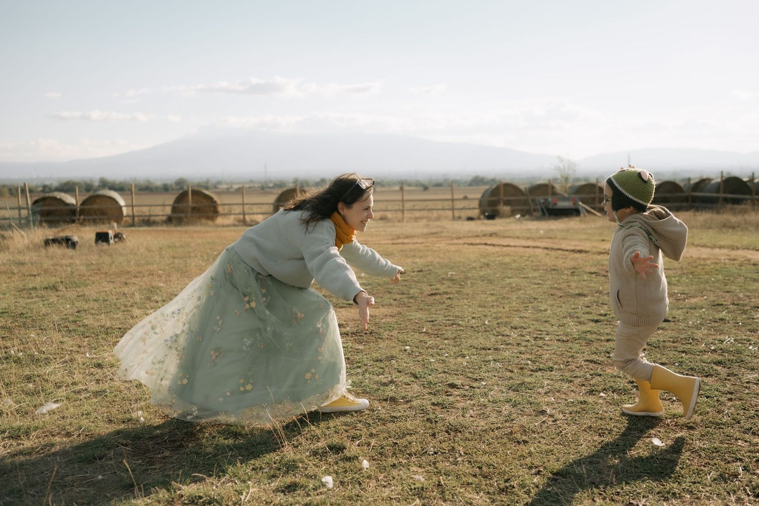 A person in a flowy white dress runs through a golden field at sunset creating a dreamy ethereal scene.