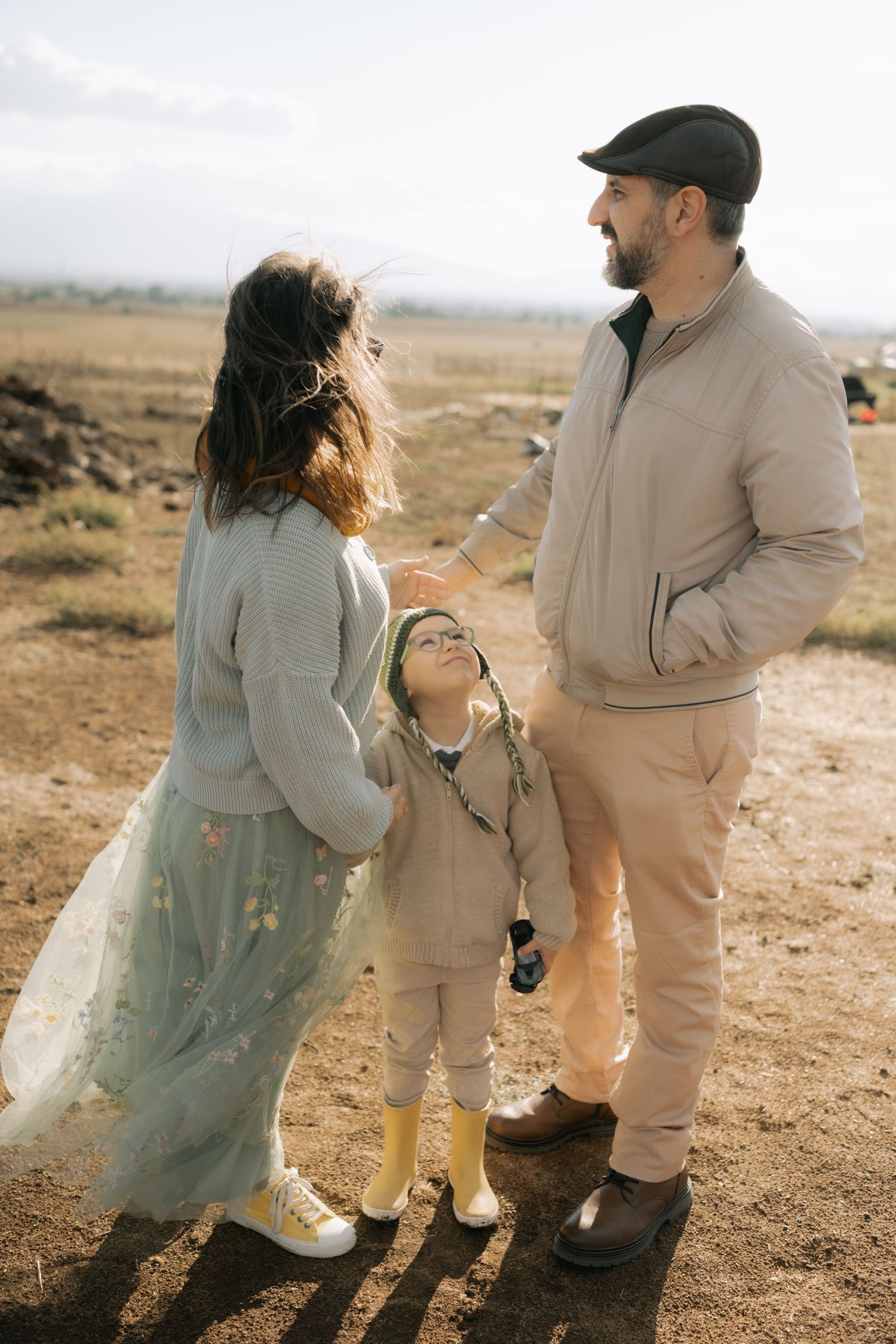 A couple dances together in a romantic desert setting wearing coordinated beige and mint green outfits.