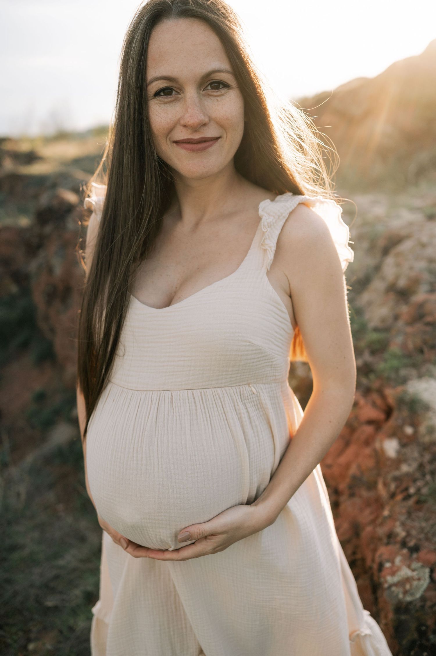 A series of maternity photos showing a woman in a white dress during golden hour sunset against a rocky backdrop.