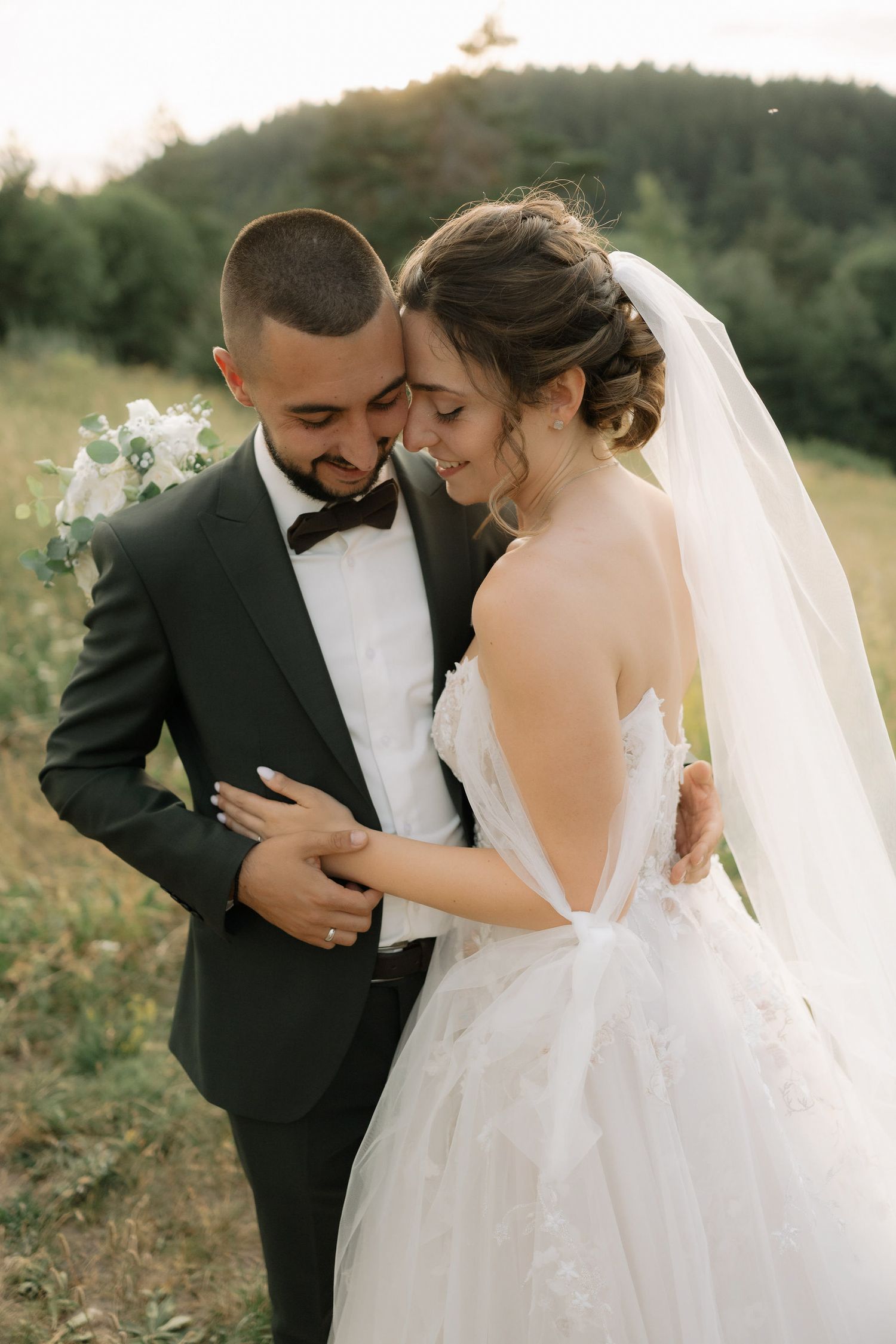 A romantic wedding couple shares intimate moments in a field during golden hour, captured in a series of candid shots.