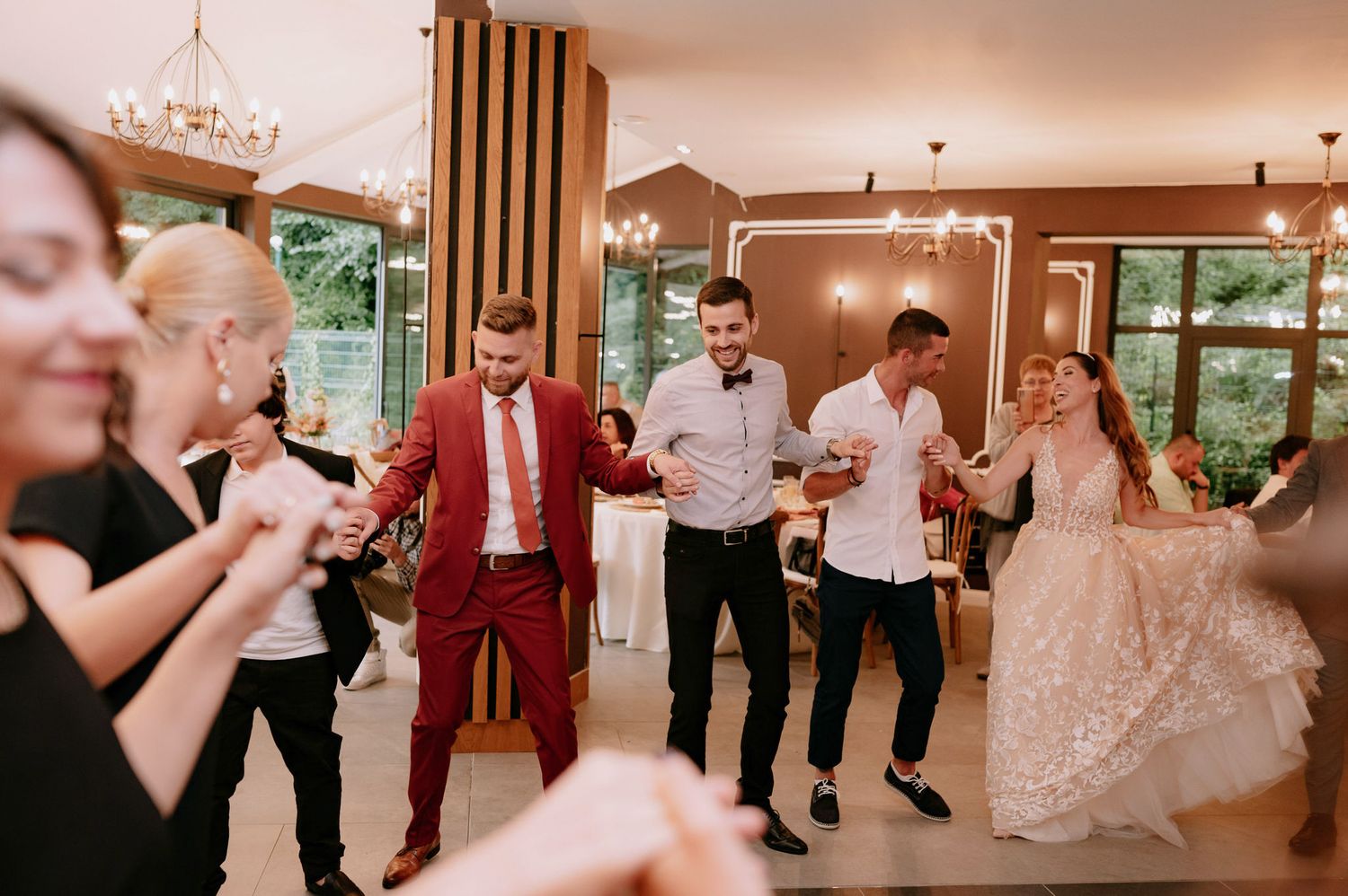Wedding party dances and celebrates together in a warmly lit reception venue during a joyous celebration.
