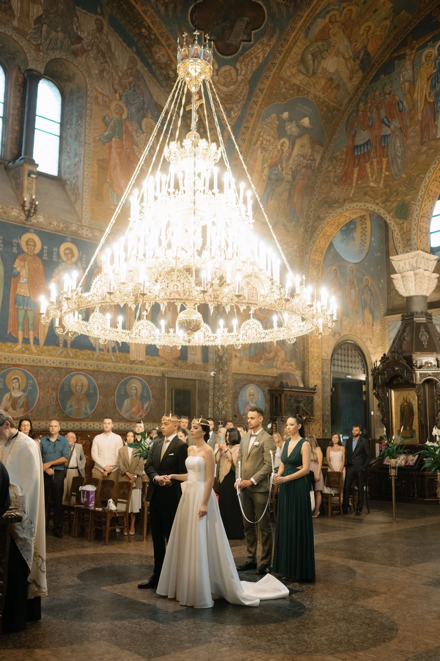 Elegant wedding ceremony in an ornate historic ballroom with crystal chandeliers and painted frescoed walls.