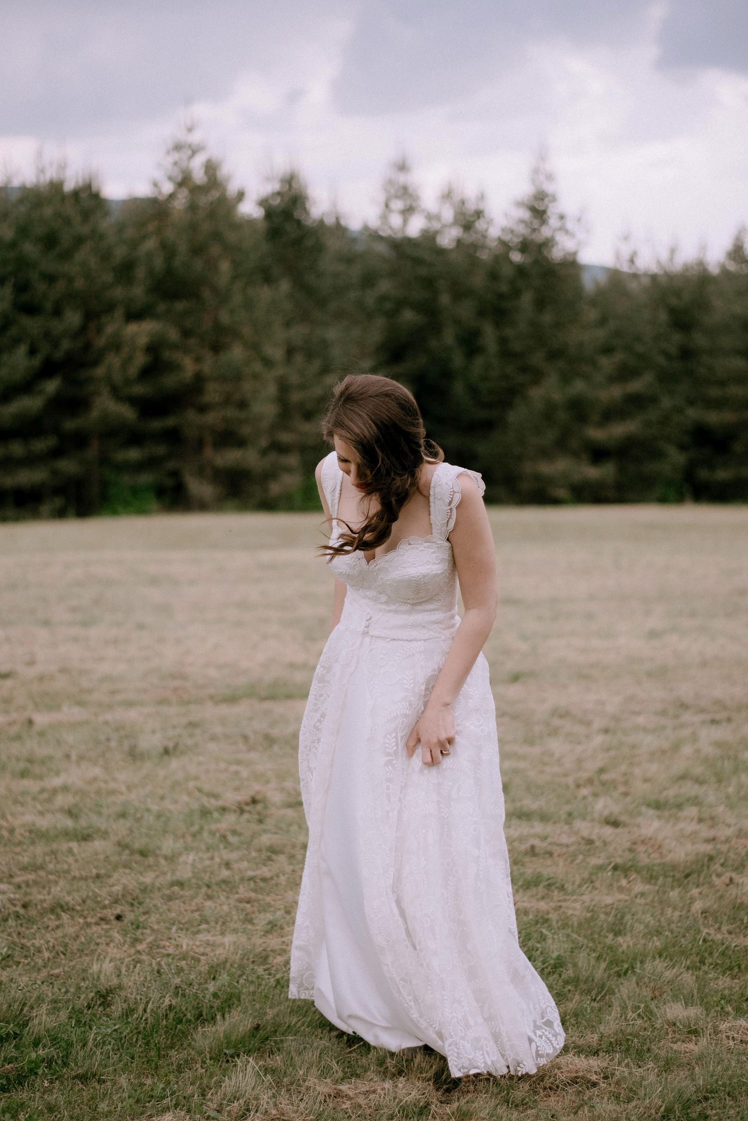 A person in a white lace dress twirls playfully in a grassy field.