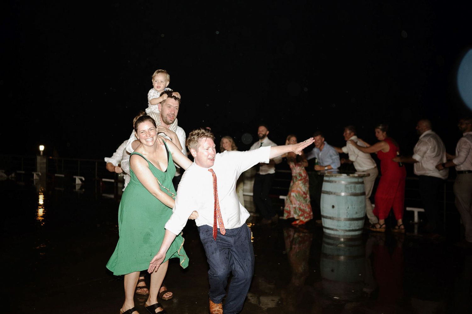 Guests dancing and celebrating at an outdoor evening party with festive lighting.