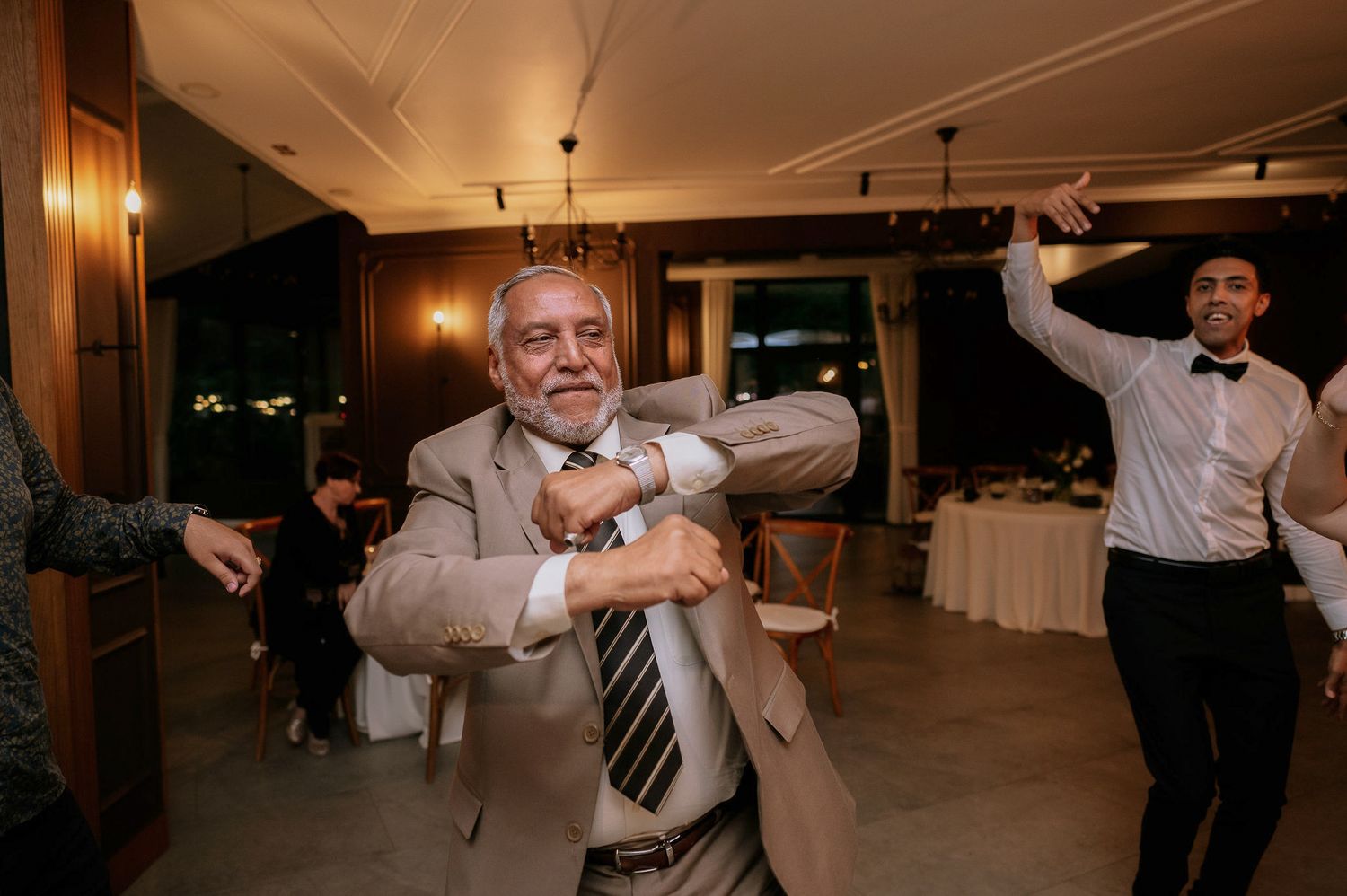 Guests dancing and celebrating with arms raised in an indoor venue.