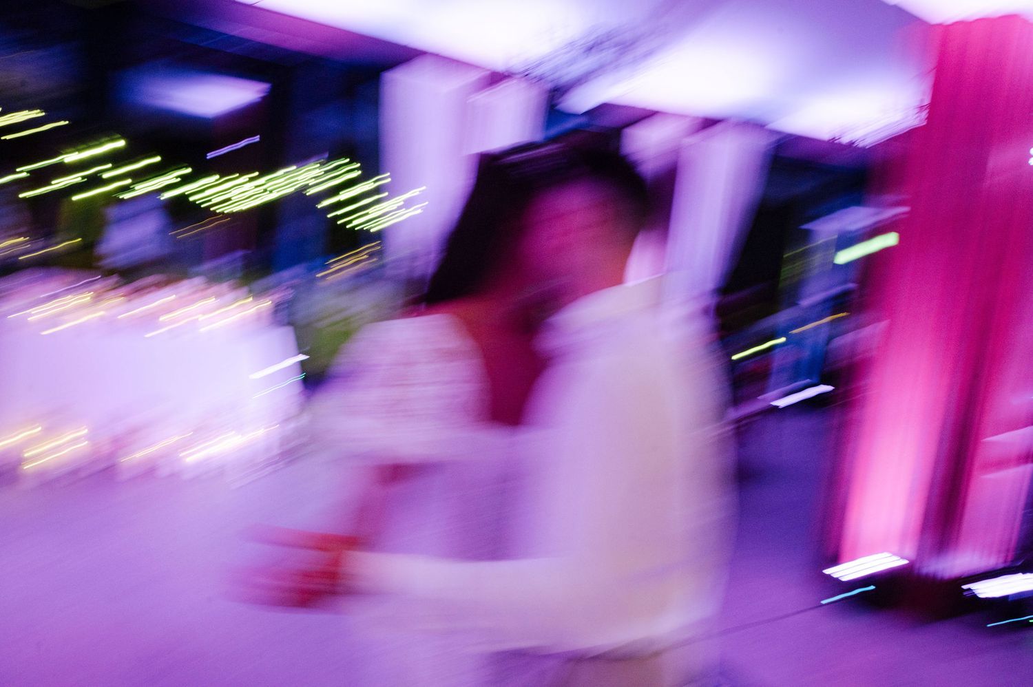 Wedding reception dance floor illuminated with vibrant purple and pink lighting during evening celebrations.