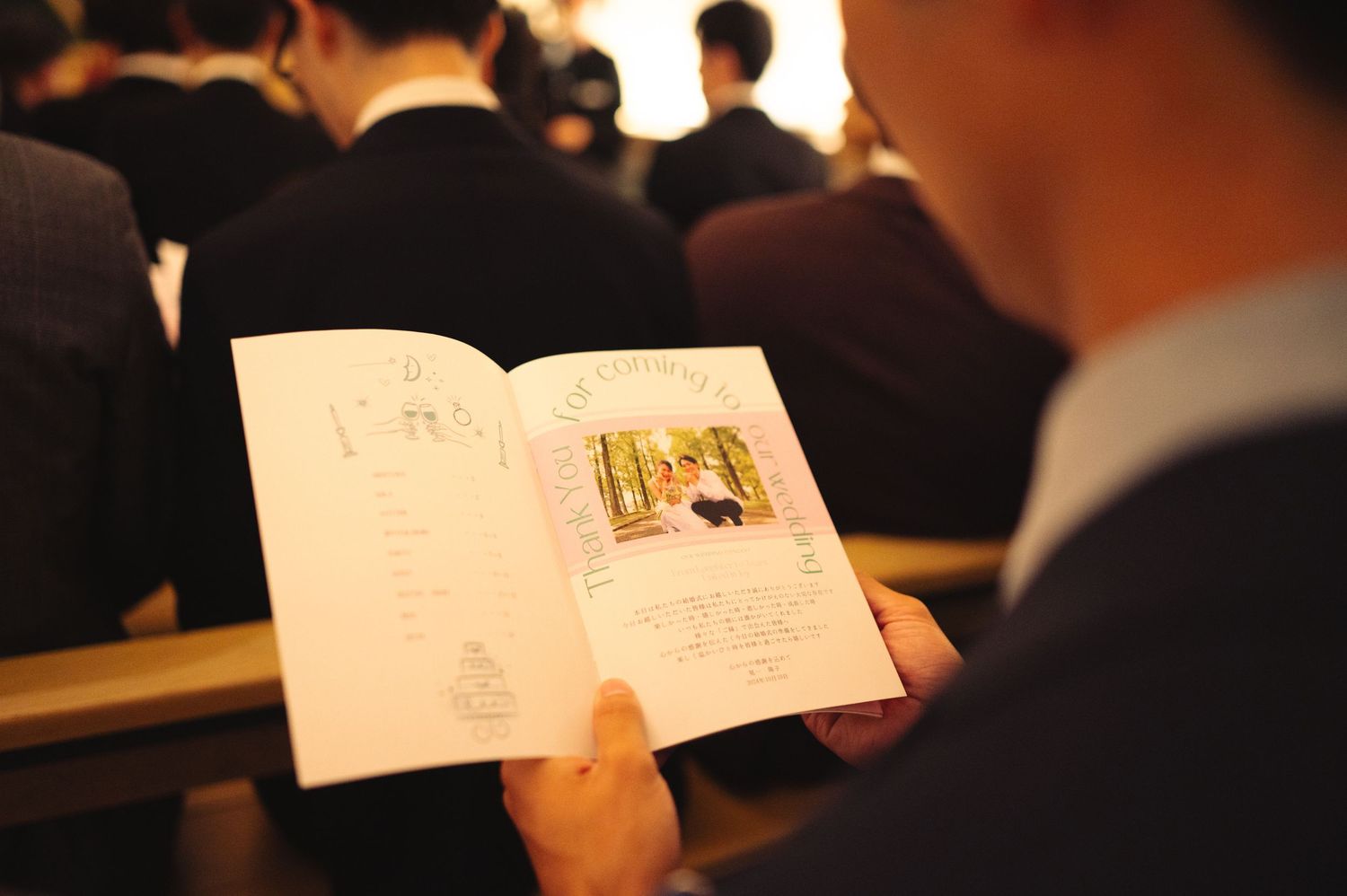 Person holding an open book or program with photos during an event.