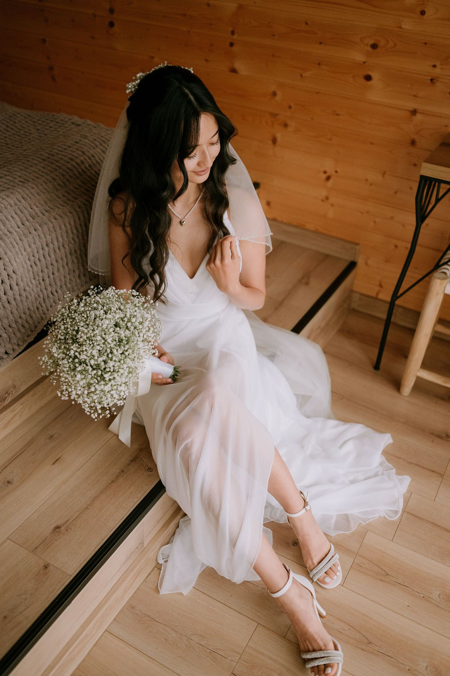 Romantic bridal pose with flowing white dress and baby's breath flowers in a wooden interior.