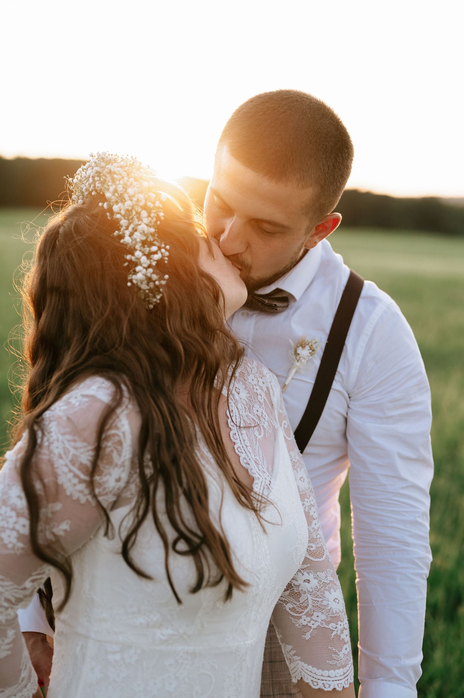 Romantic sunset portrait of wedding couple in a meadow with soft lighting.