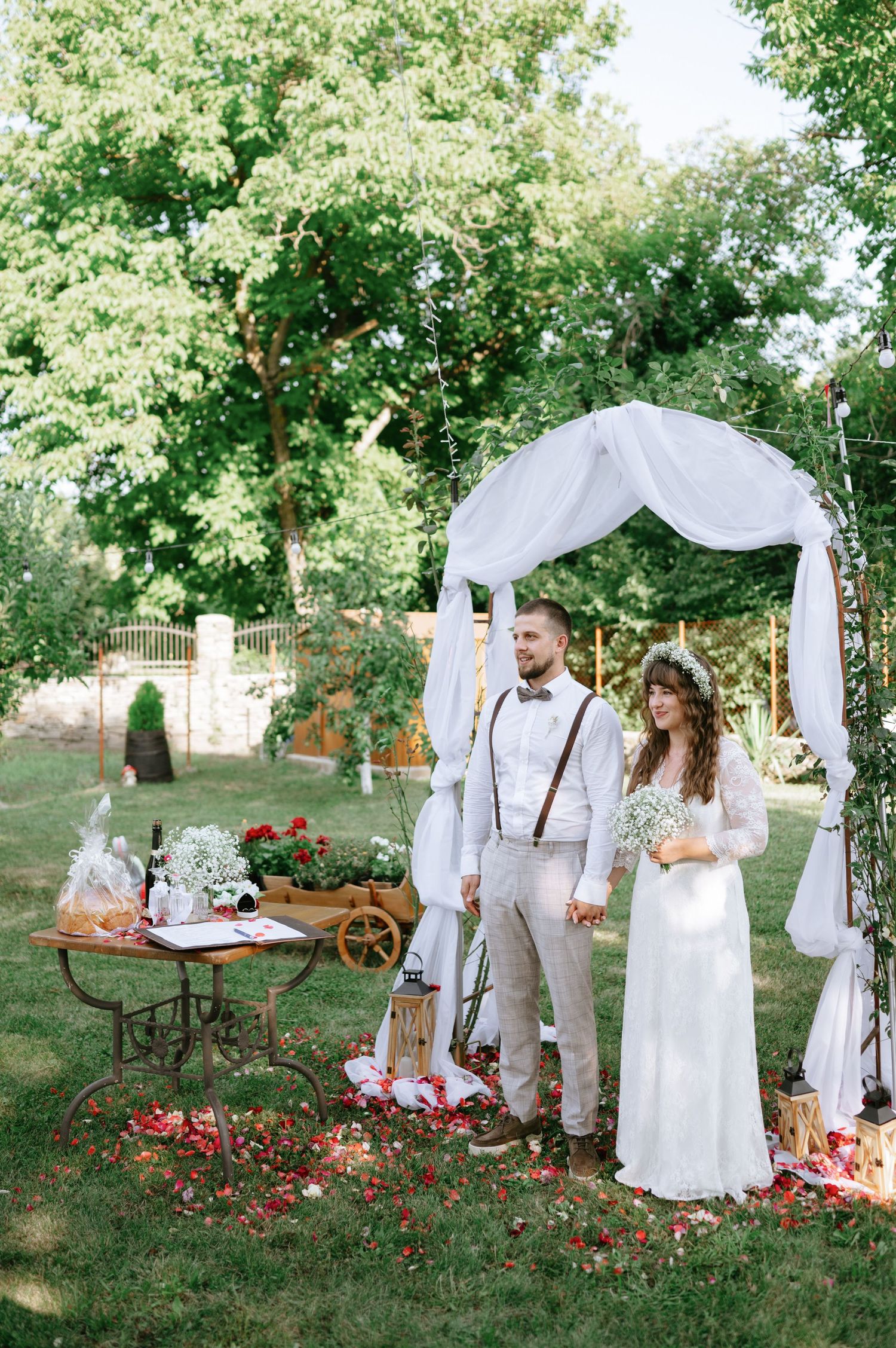 An elegant garden wedding scene with white fabric archway and rustic wooden accents.