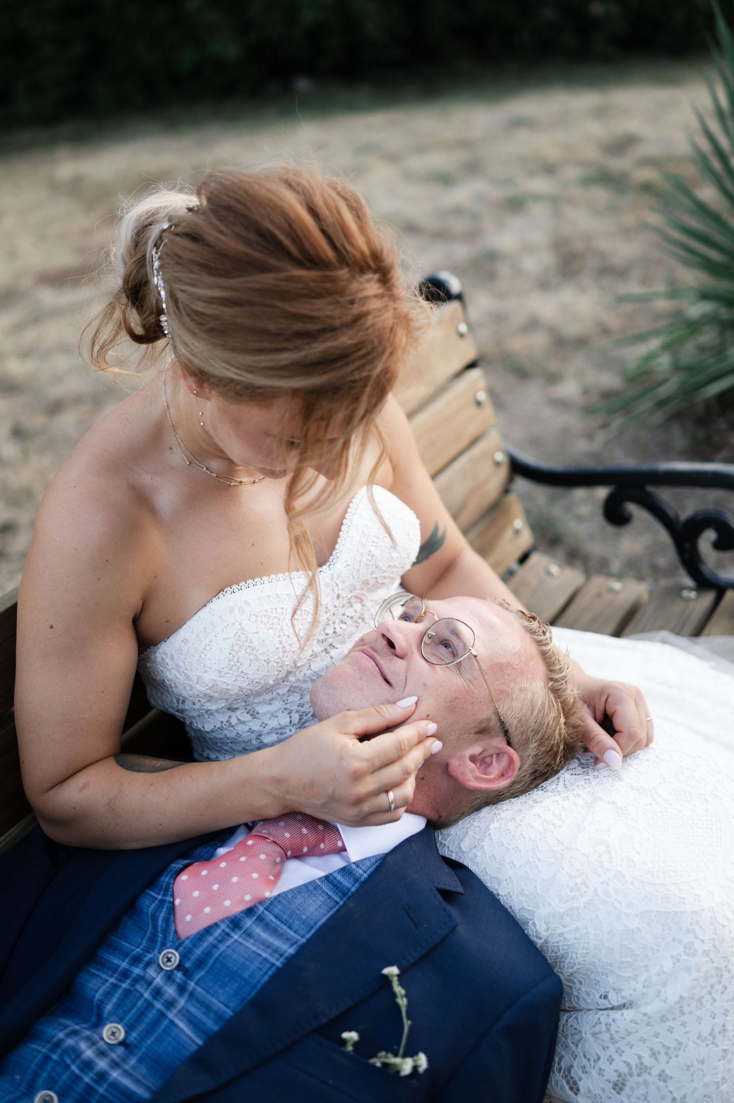 Intimate moment between newlyweds relaxing on a garden bench.