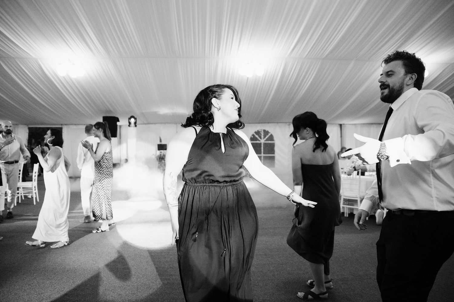 Silhouettes of wedding guests dancing and celebrating at reception venue.