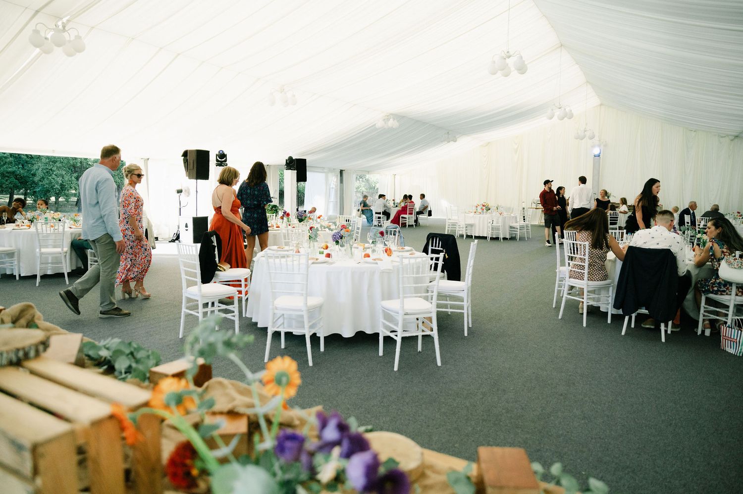 Wide view of wedding reception tent showing guest seating and decorative setup.