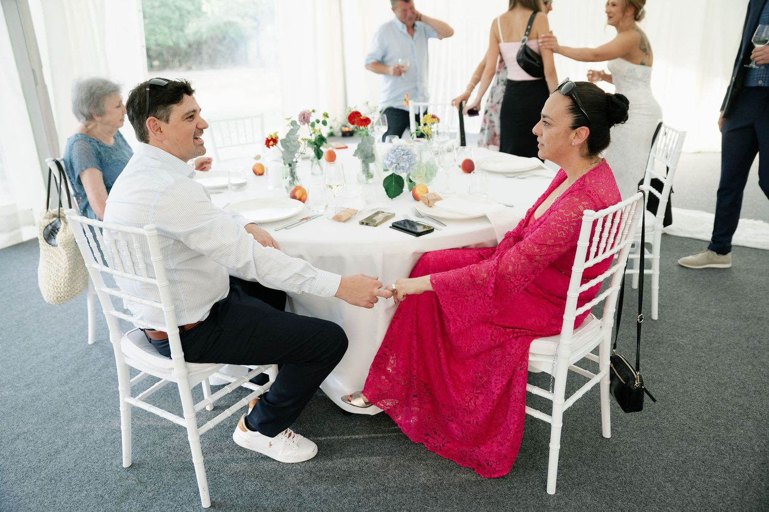 Wedding guests seated at decorated tables during an indoor reception celebration.