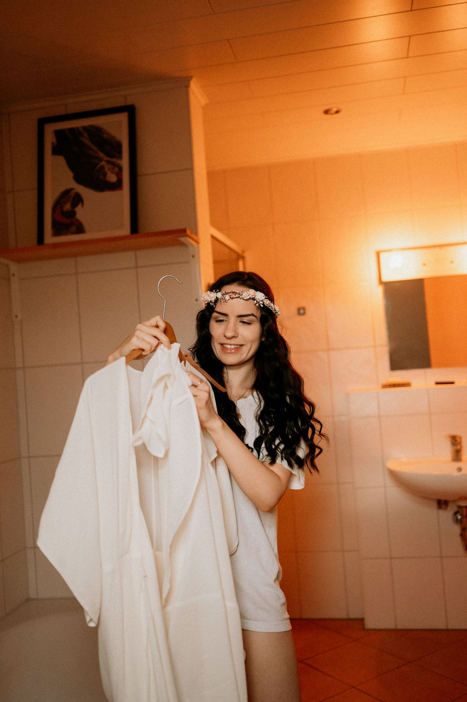 Person interacting with white clothing in a bathroom with warm lighting.