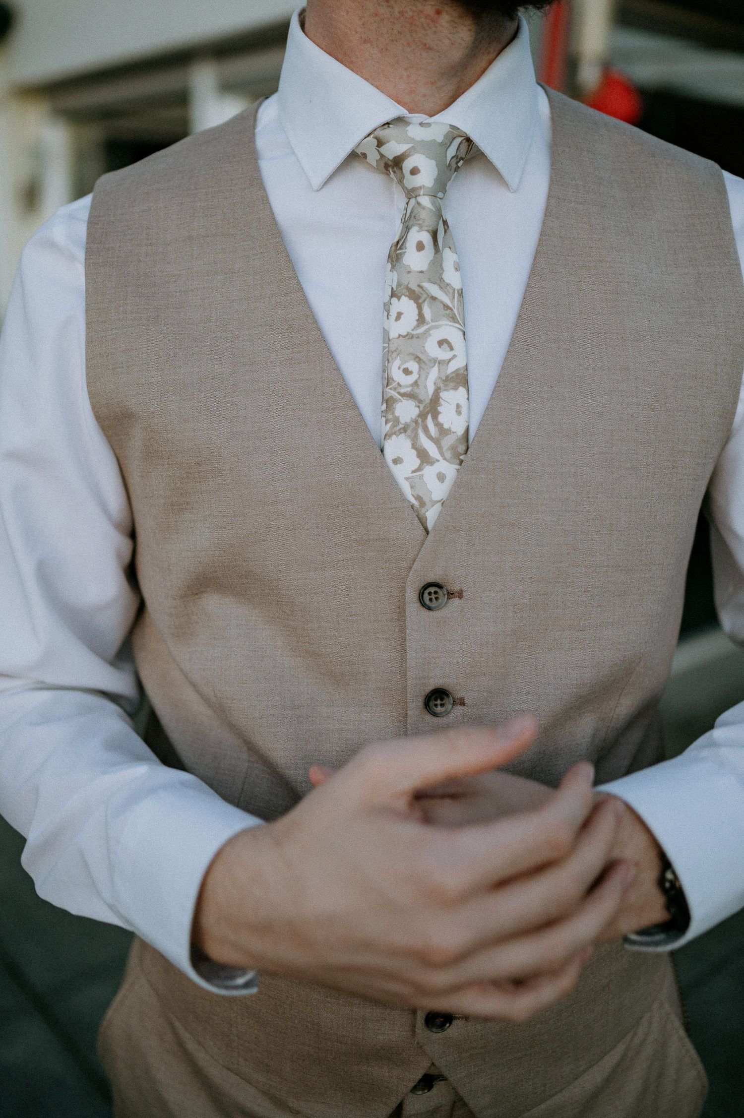 Close-up details of formal wear including gray vest and floral patterned tie.