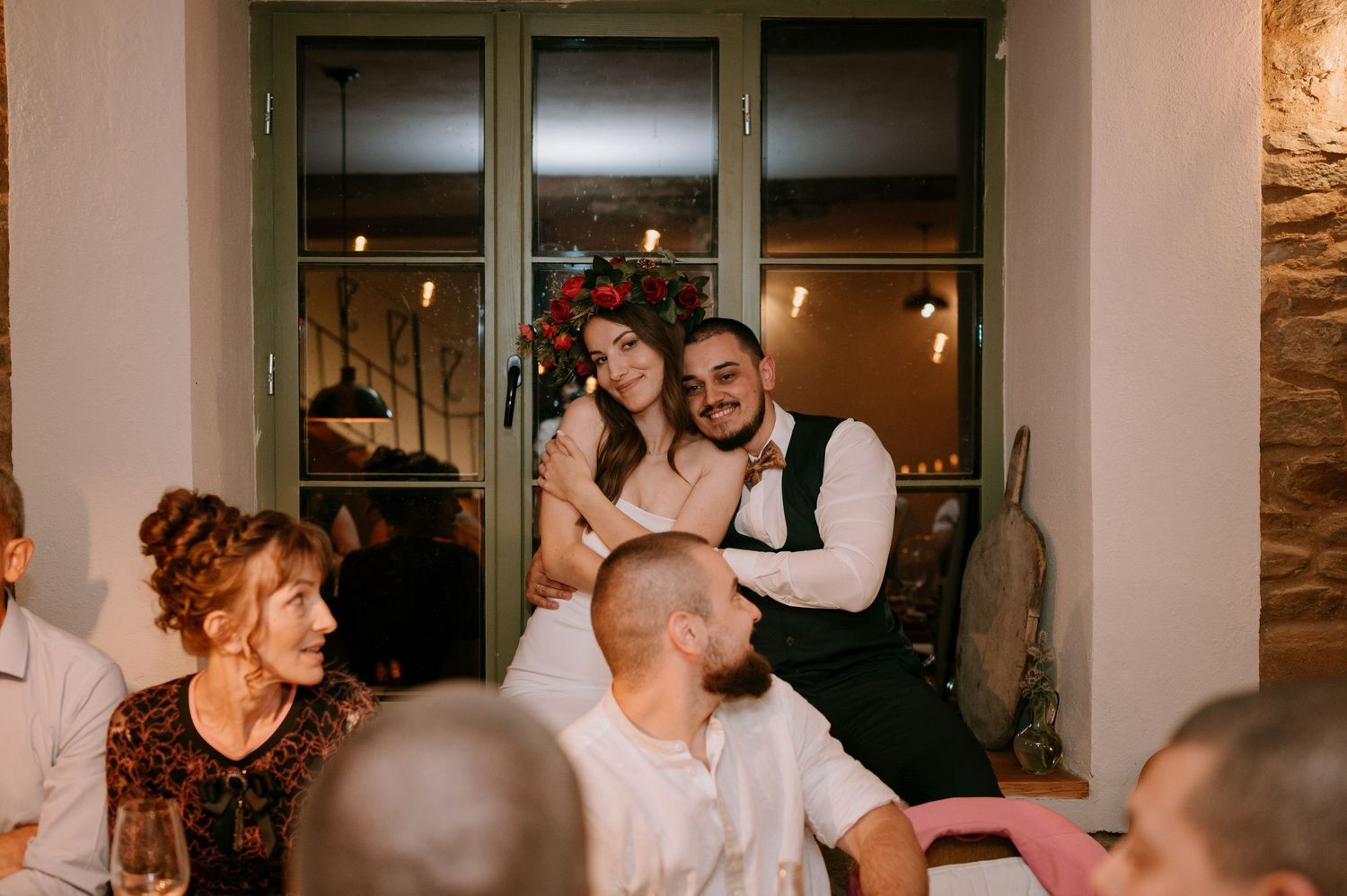 People dancing and celebrating in a warmly lit indoor venue with large windows.