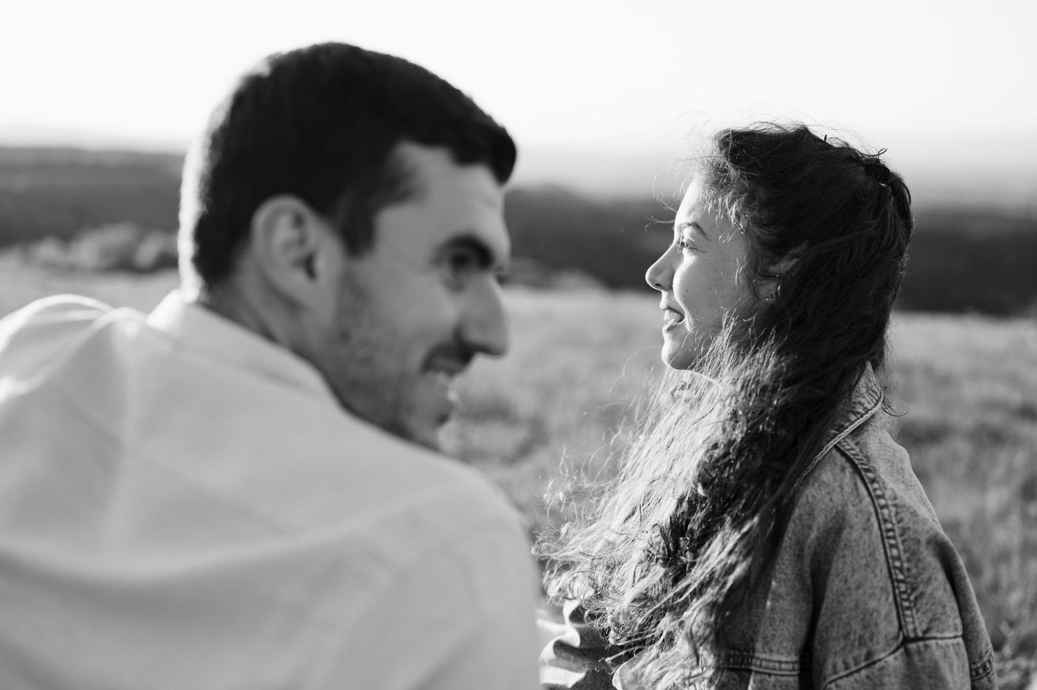 Black and white photo of two people sharing a joyful moment together outdoors in natural lighting.