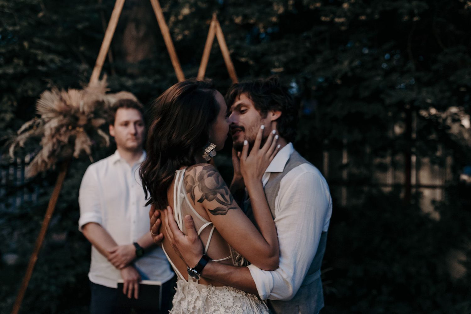 A romantic couple embraces intimately in a dark outdoor setting during a wedding photoshoot.