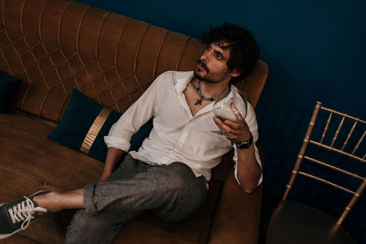 Person lounging on vintage brown leather sofa making expressive gesture.