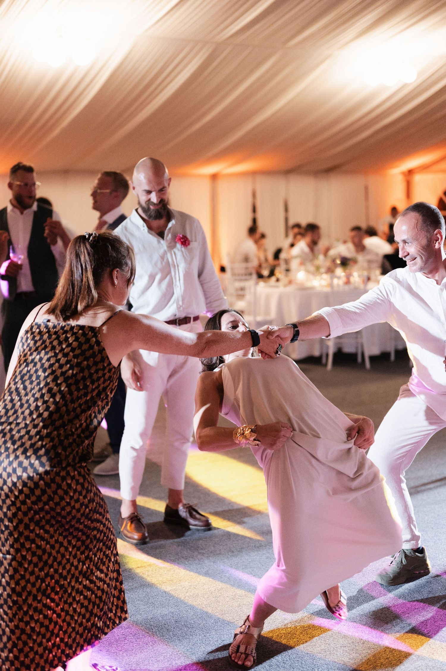 Group of people practicing yoga poses together in a white tent with warm lighting during a wellness event.