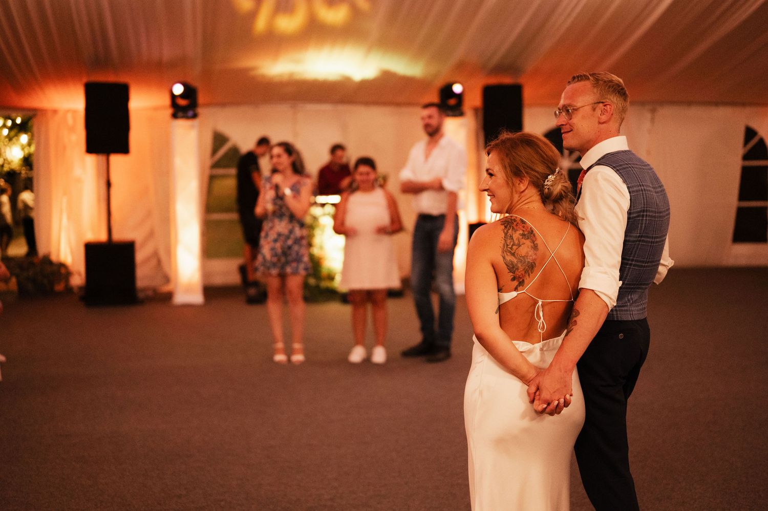 A couple shares a romantic dance on the illuminated dance floor at an elegant wedding reception.