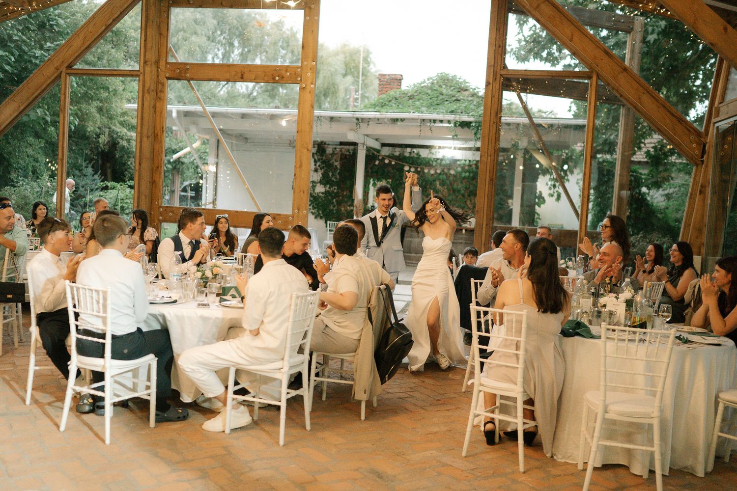 A panoramic view of an elegant wedding reception with white tables and chairs set inside a rustic wooden pavilion.