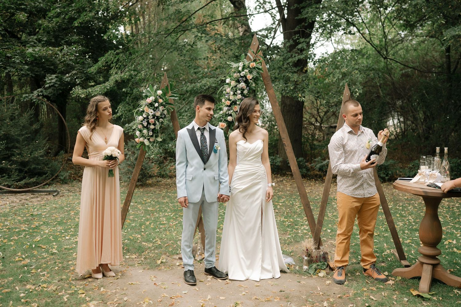 A group gathers in a lush garden setting for a summer wedding celebration with natural greenery surroundings.