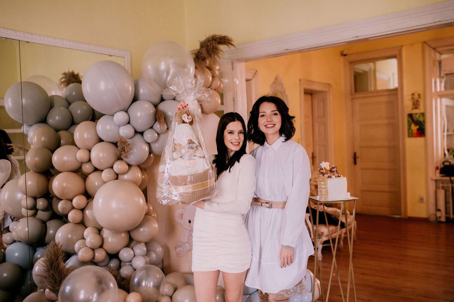 White balloon decorations adorn an elegant indoor event space with neutral tones and warm lighting.