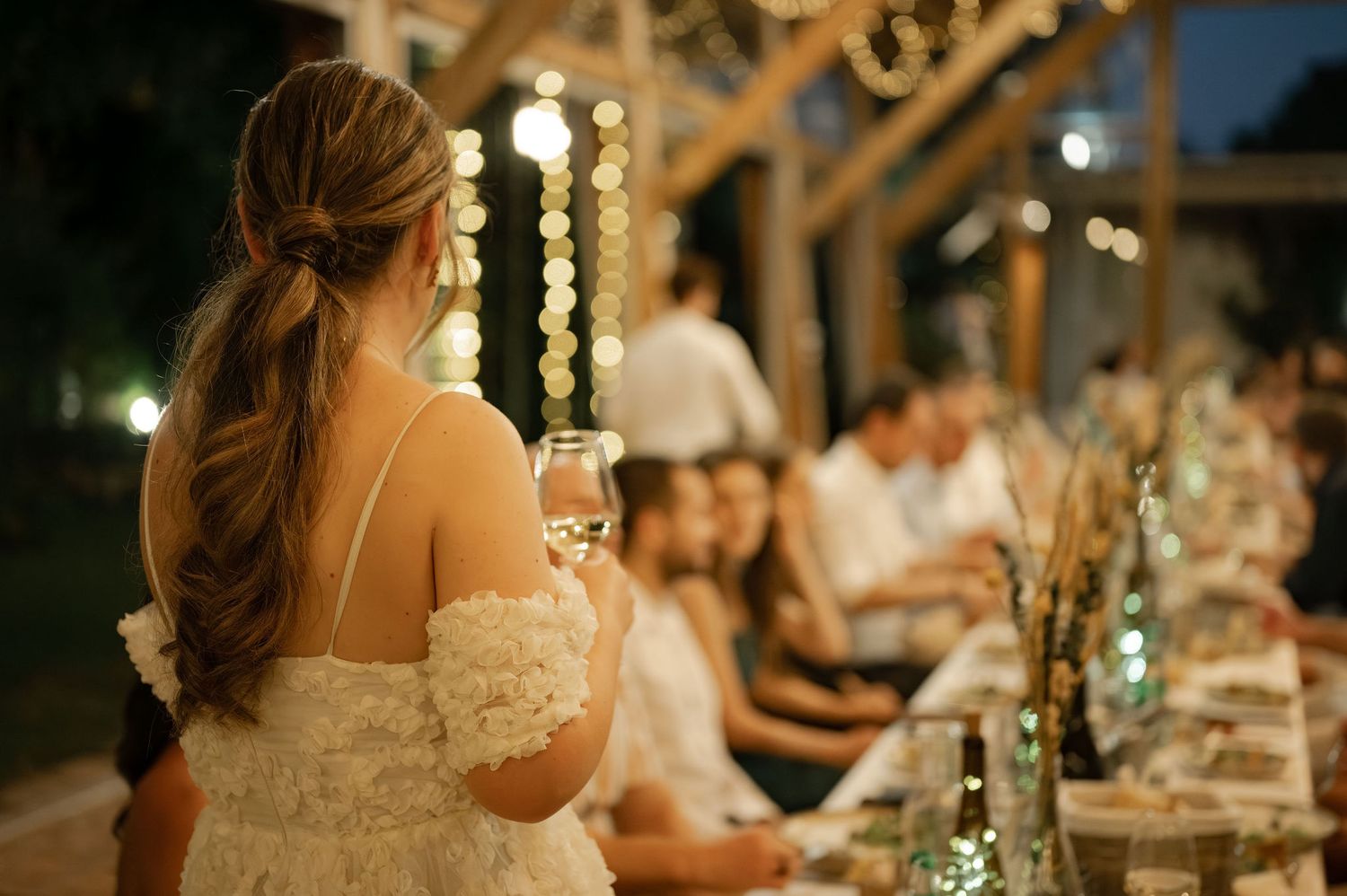 Elegant wedding reception dinner setup with glowing candles and rustic decor at dusk in an outdoor venue.