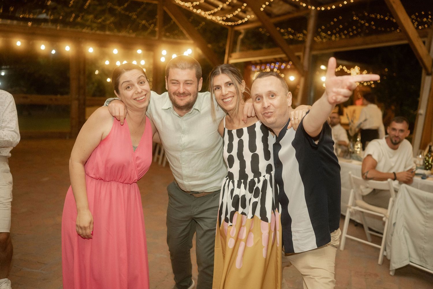 Wedding reception guests dance and celebrate under string lights in a rustic barn venue.
