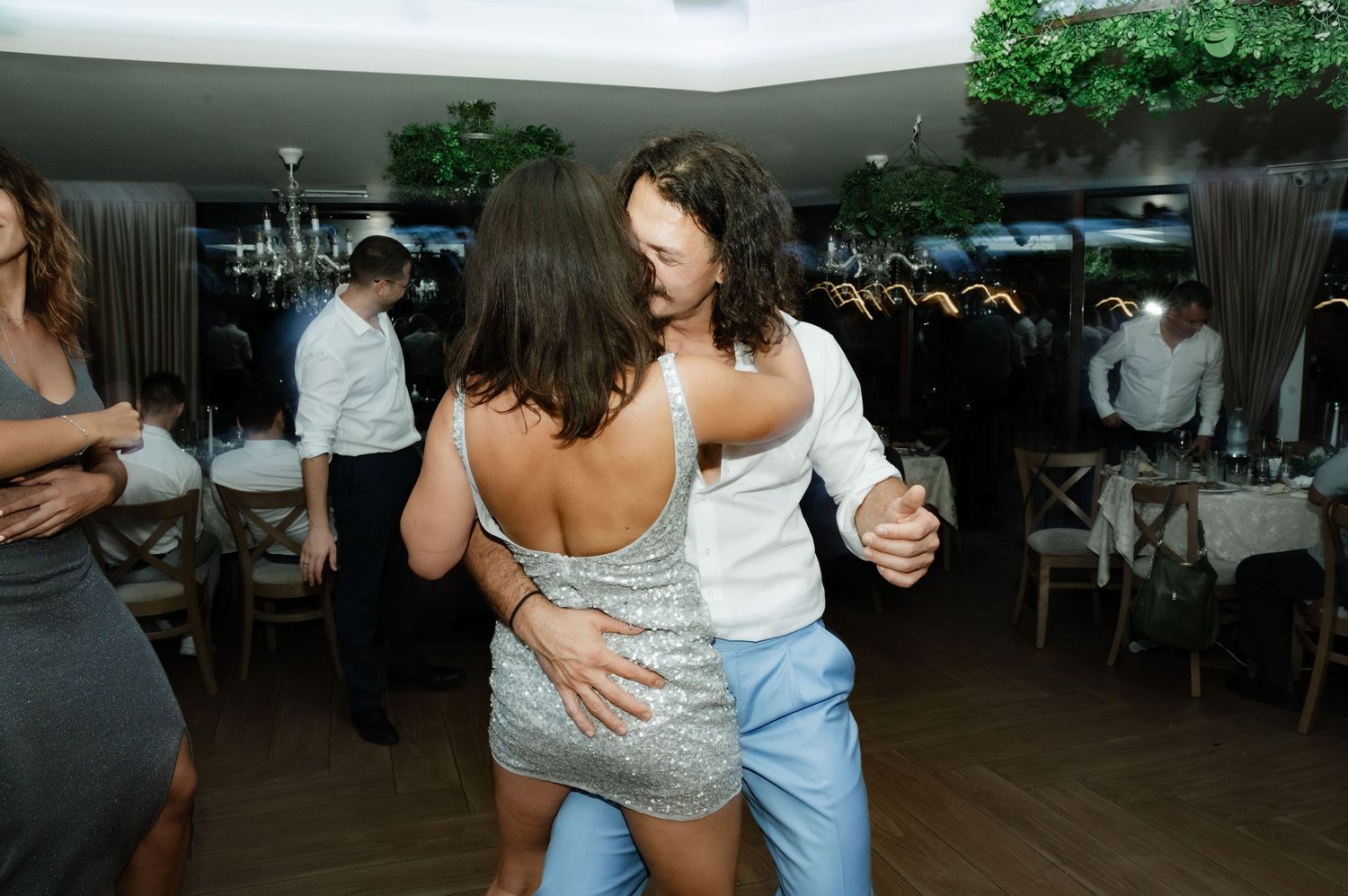 Couples dancing together on a wooden floor at an indoor event space.