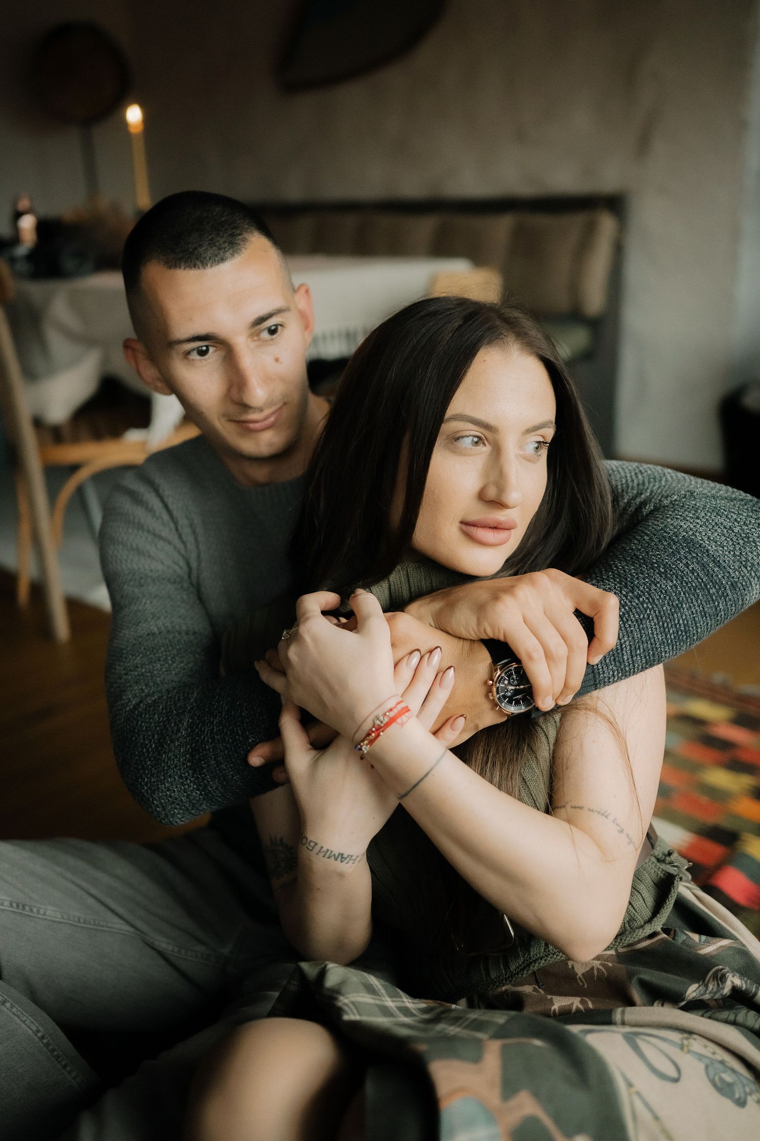 Intimate couple sharing tender moments together on a couch in moody lighting.