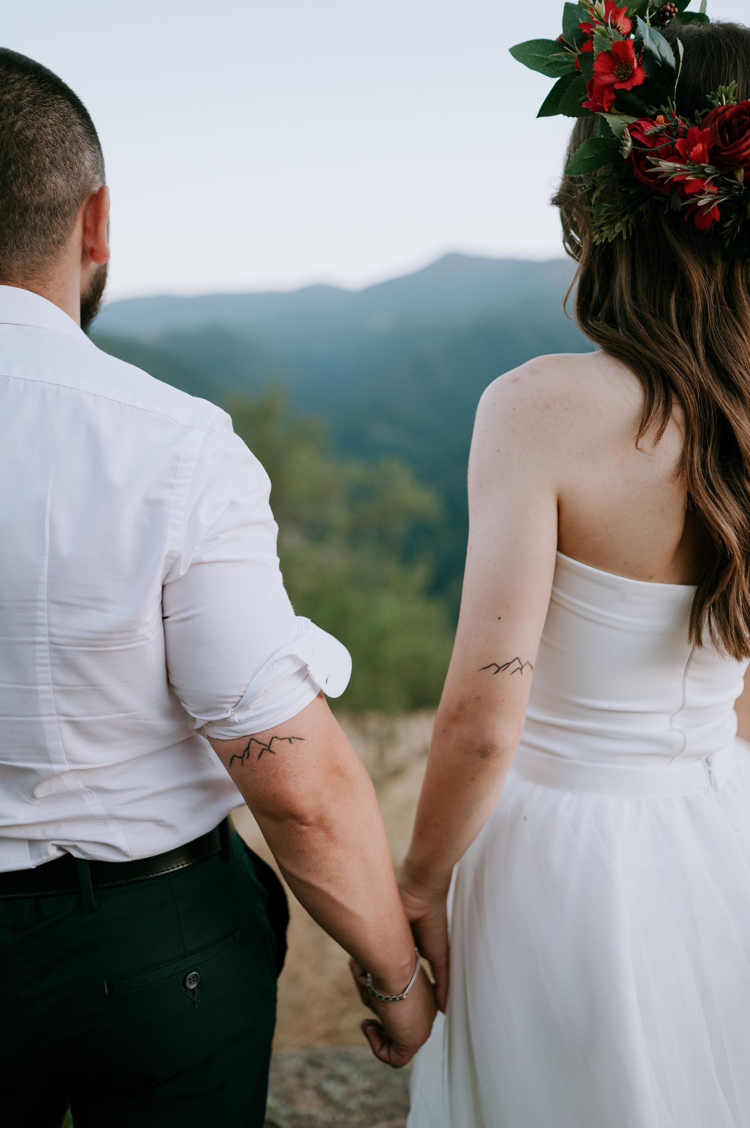 Side view of couple holding hands with mountain landscape behind them.