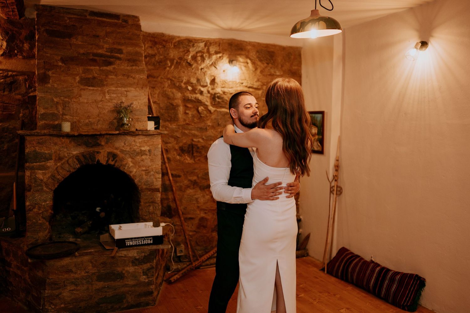 Couples dancing in a cozy space with stone walls and pendant lighting.