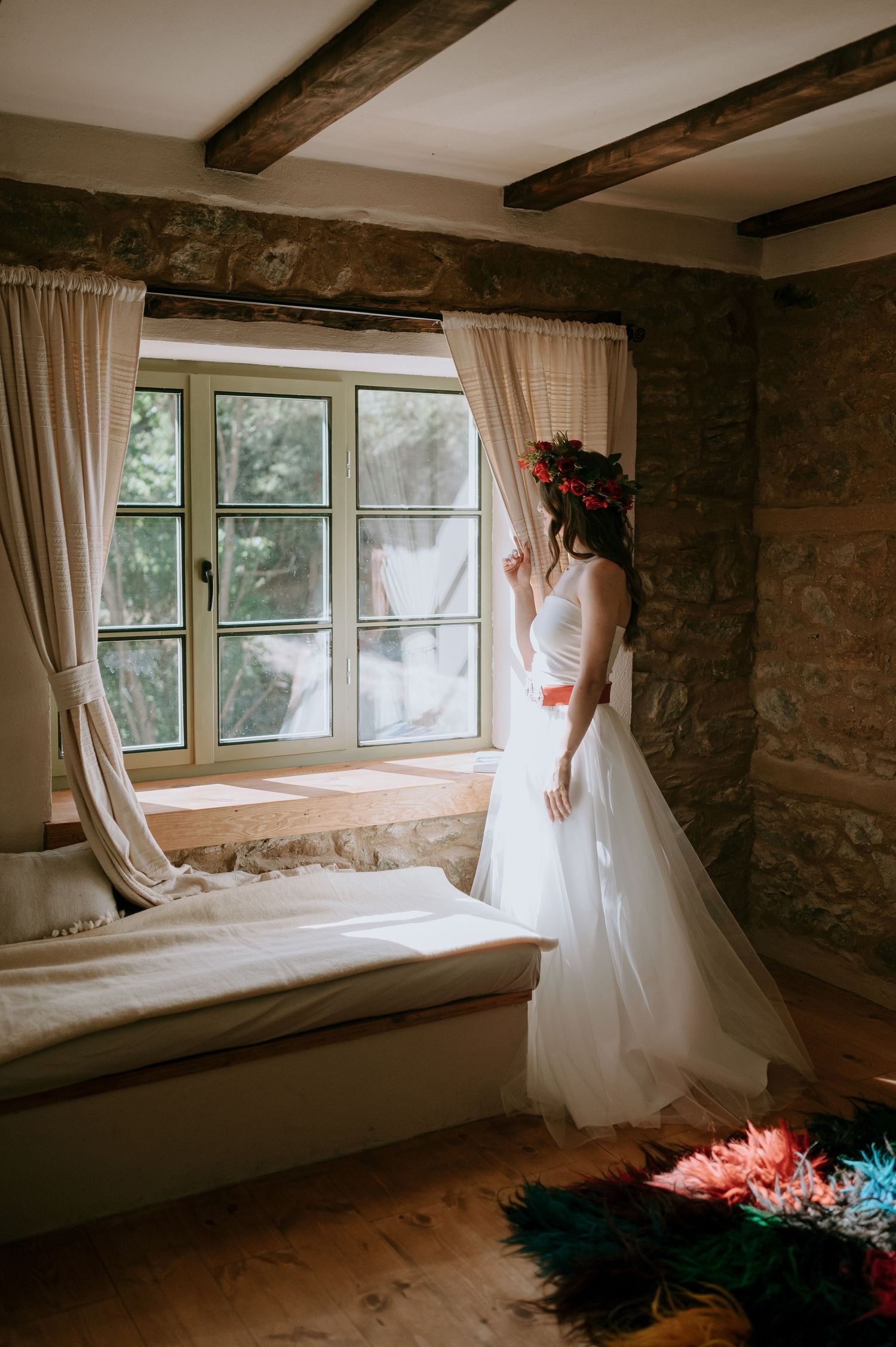 White wedding dress silhouette against rustic stone wall and window with natural light.
